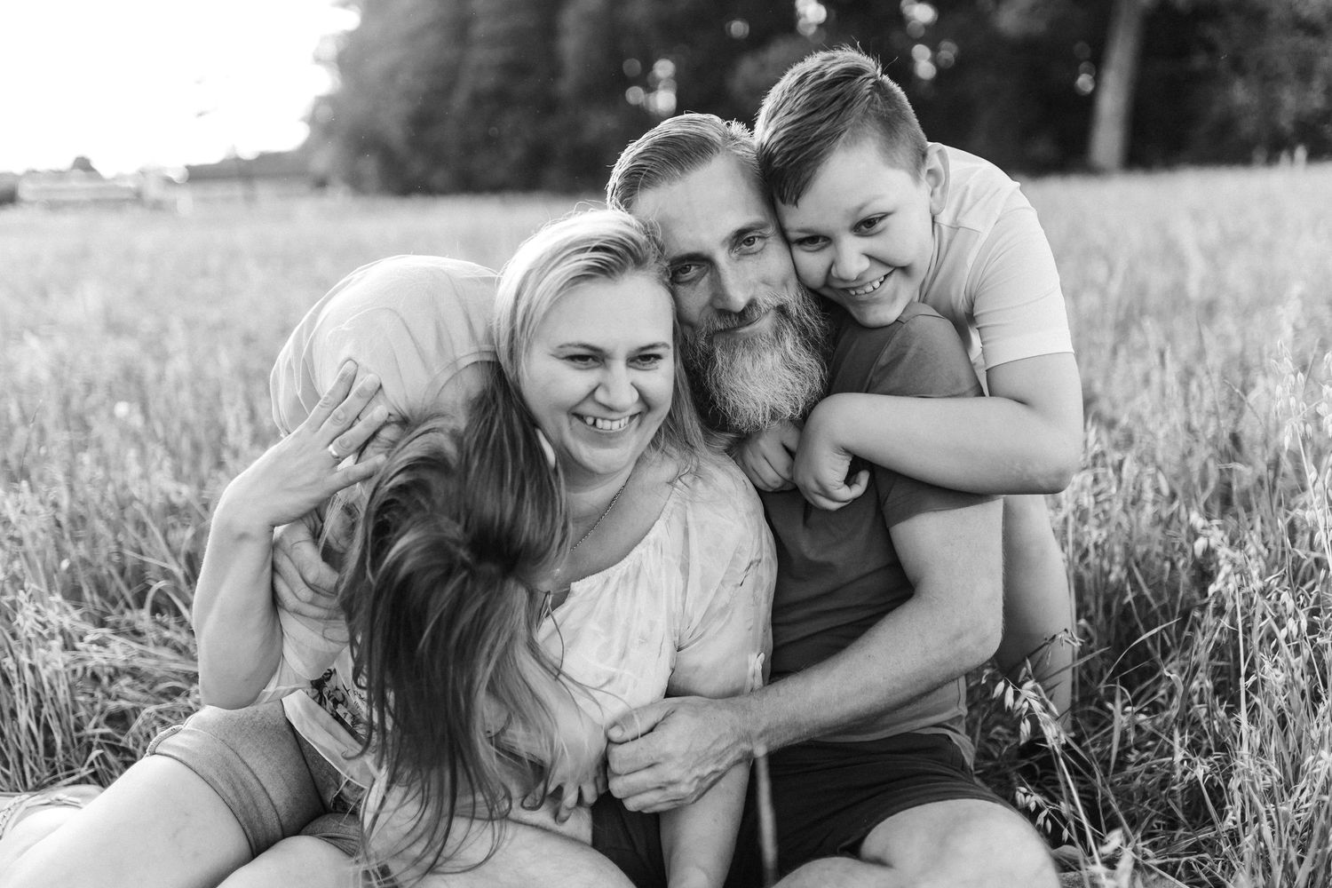 A family shares candid moments together in a sunny field.