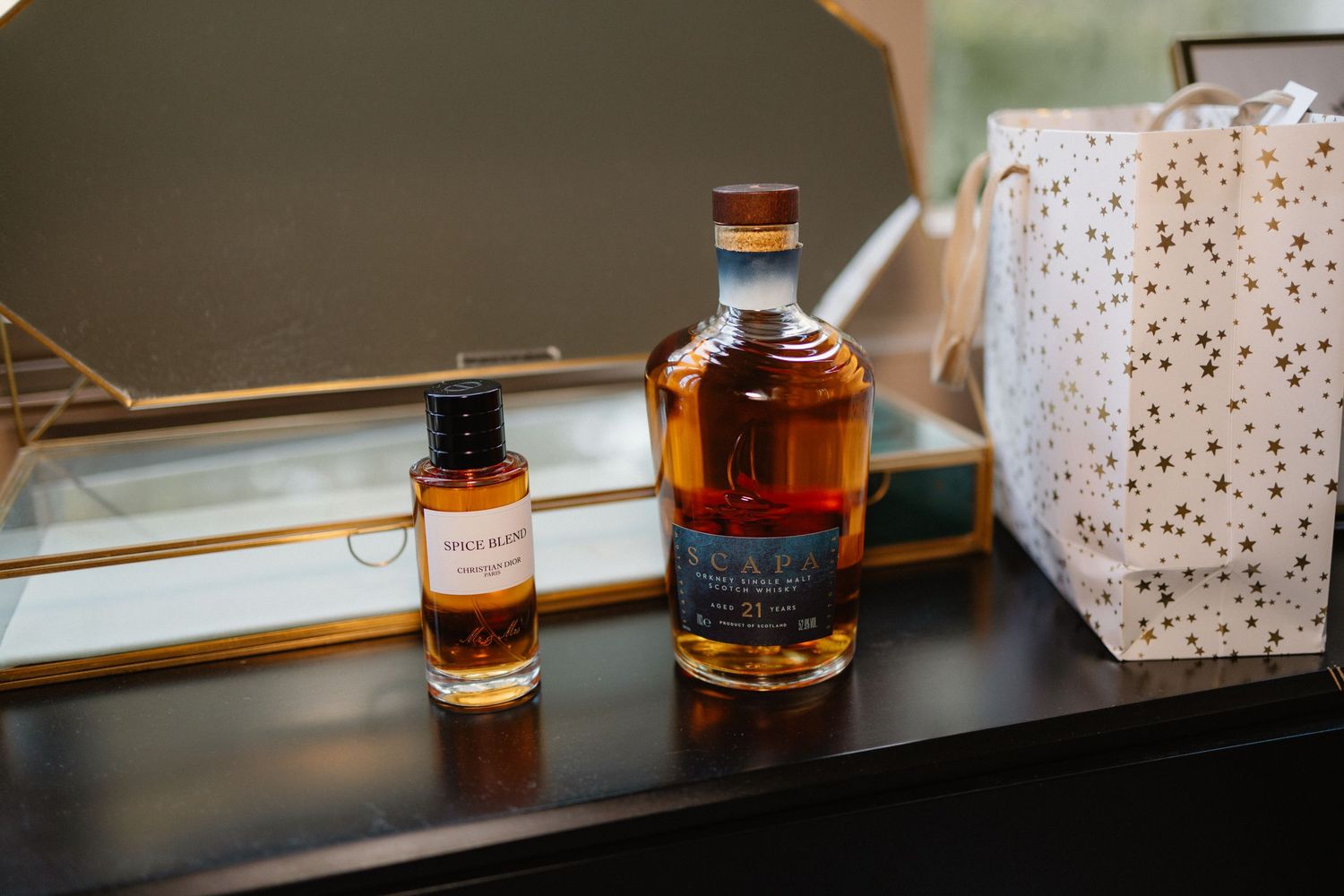 Two bottles of premium whisky displayed on dark dresser with gold-star gift bag at wedding celebration.