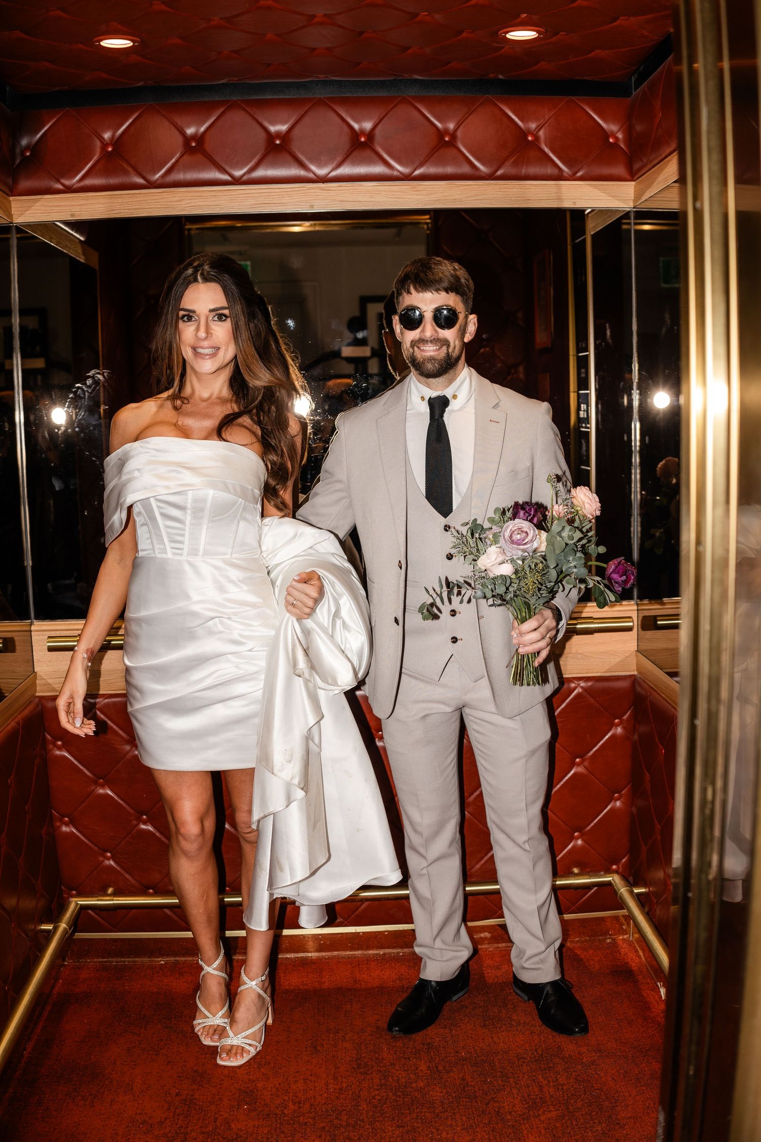 Wedding couple walking through an elegant venue with red leather and gold trim.