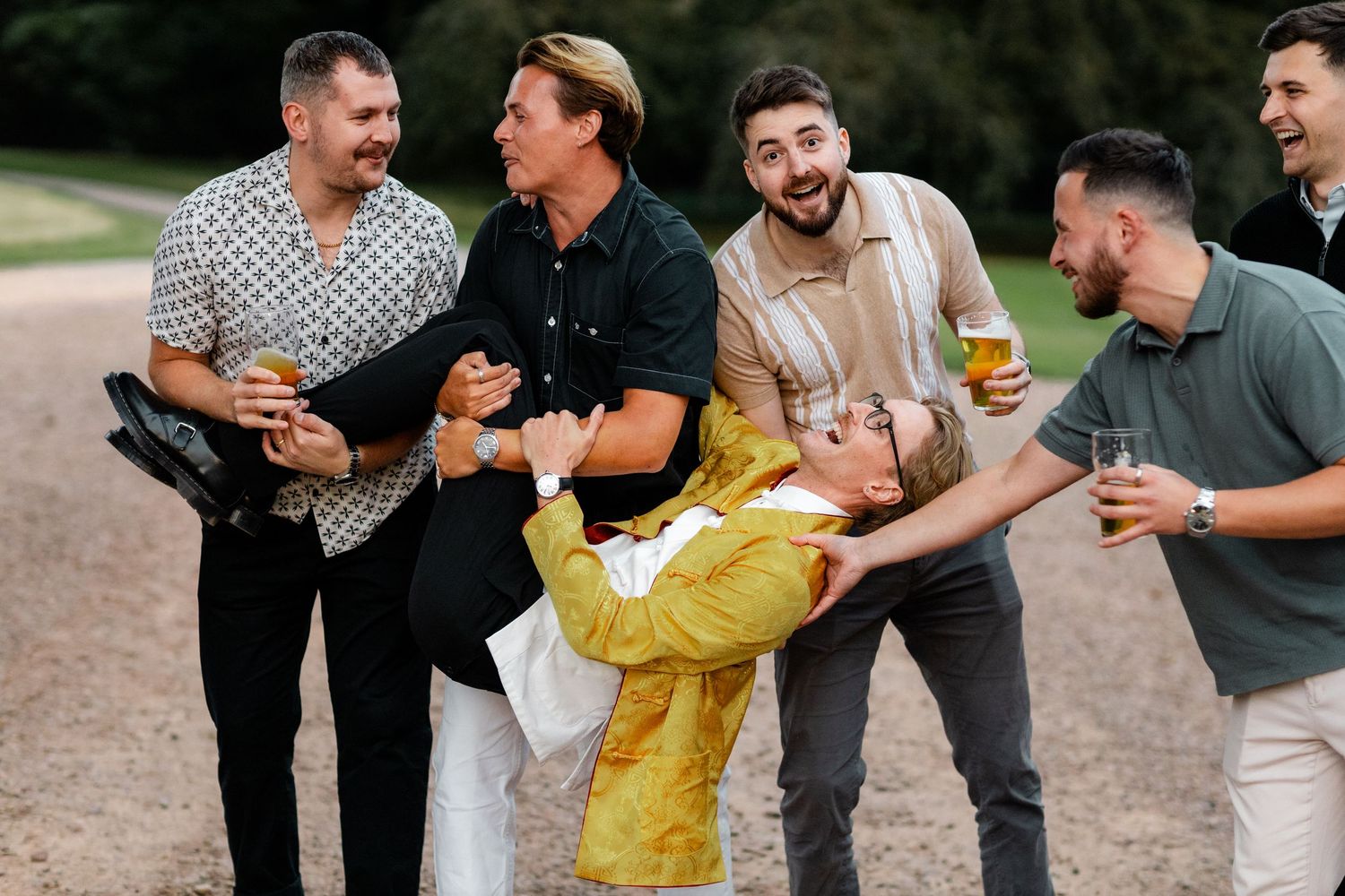 A celebratory moment captured outdoors with friends laughing and carrying someone in yellow.