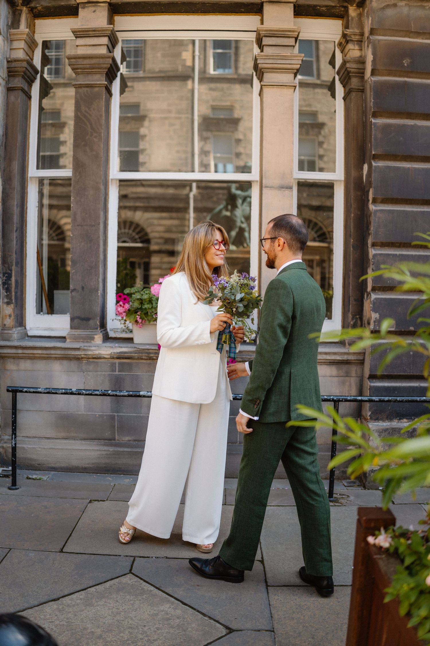 Wedding couple sharing a moment outside historic stone building with columns.