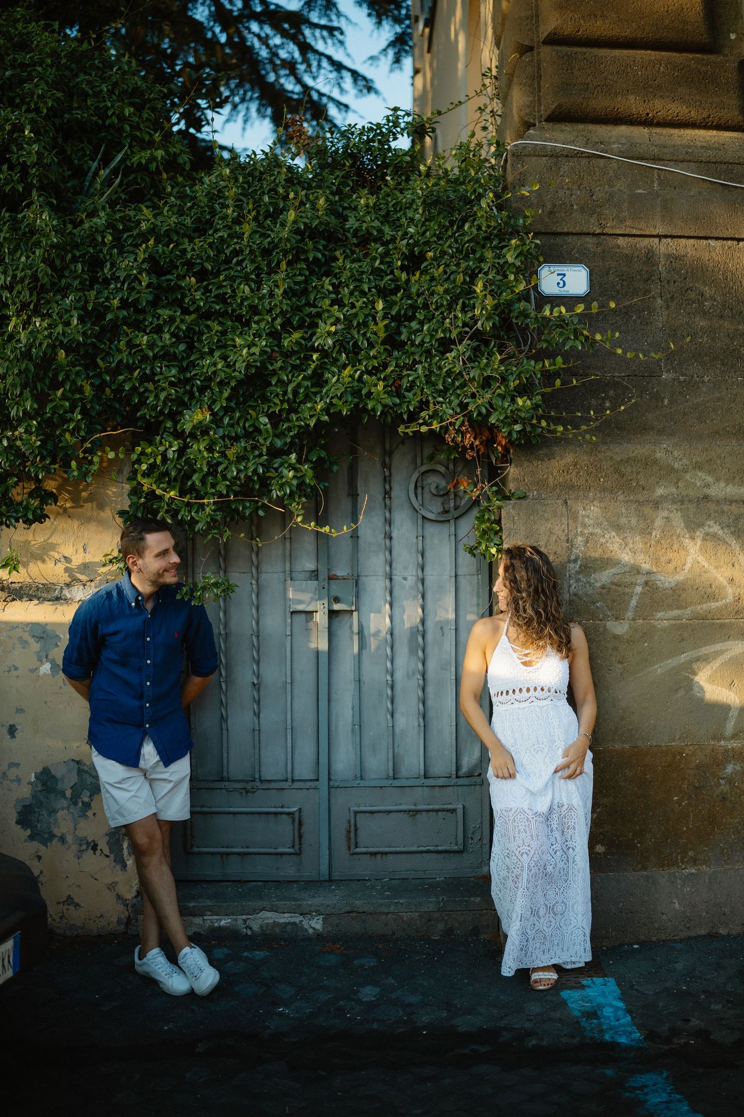 Romantic couple poses against rustic green doors and stone walls in artistic photography.