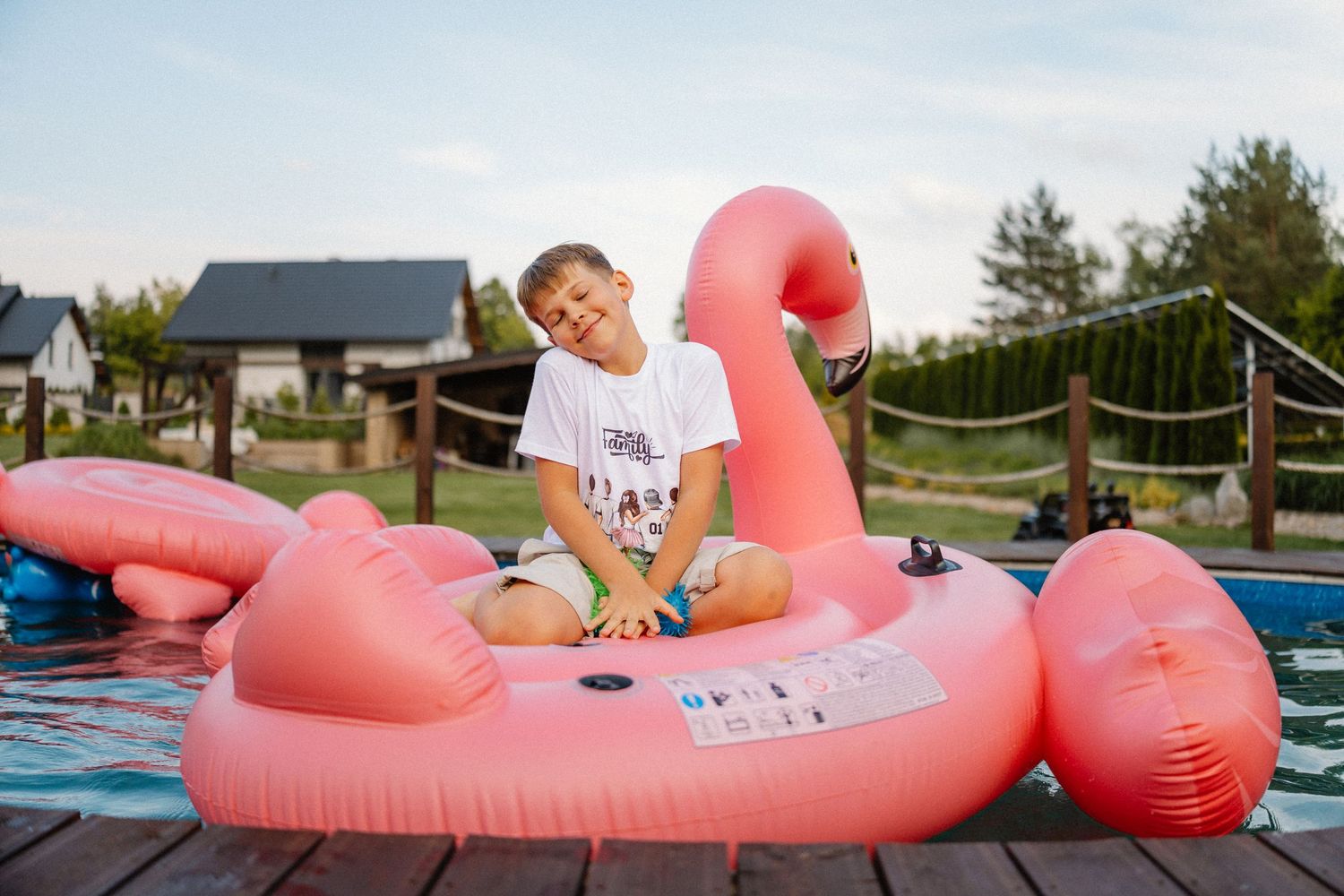 People enjoying a summer day on a large pink flamingo pool float.