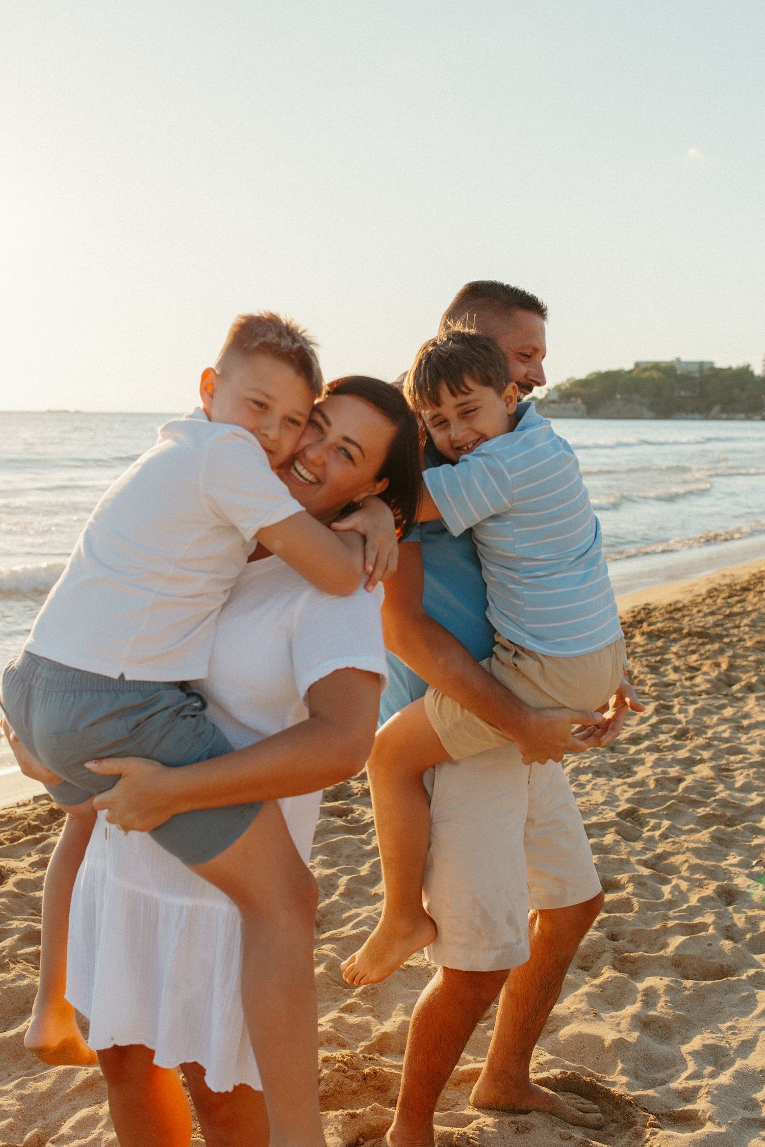 A family plays and hugs together on a sunny beach.