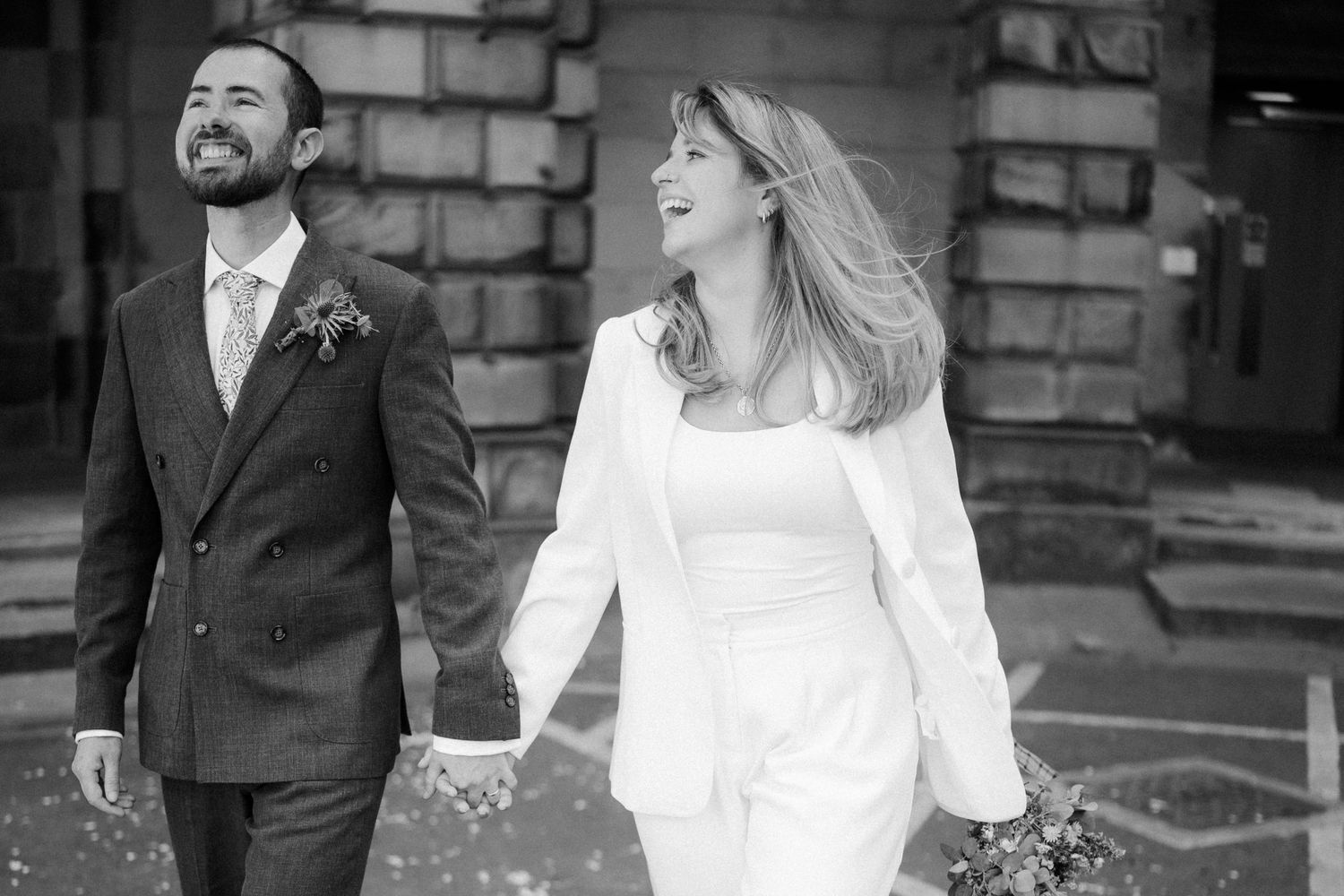 A couple walking along a stone path in formal attire.