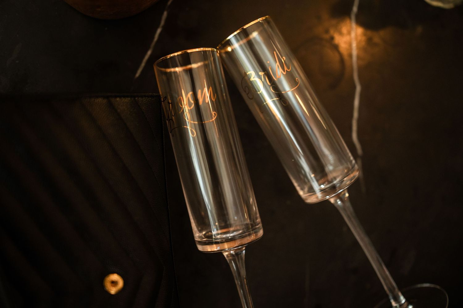 Wine glasses clink together in a celebratory toast at an evening event.