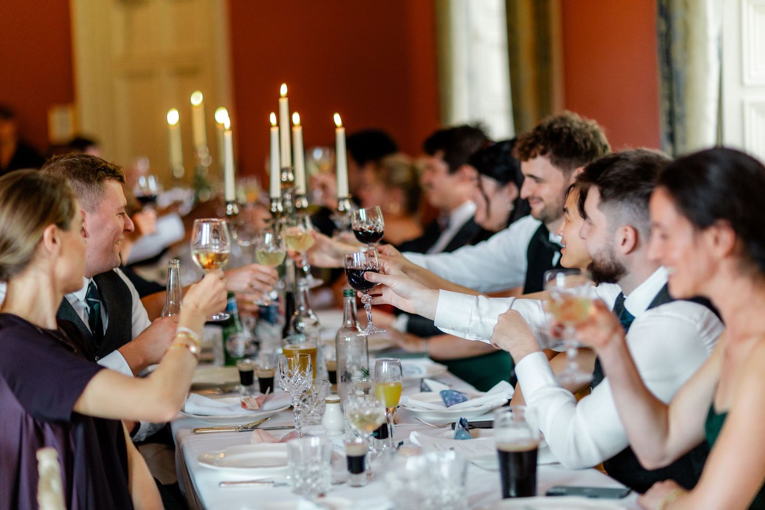 Wedding reception guests seated at elegant tables with white linens and candlelight.