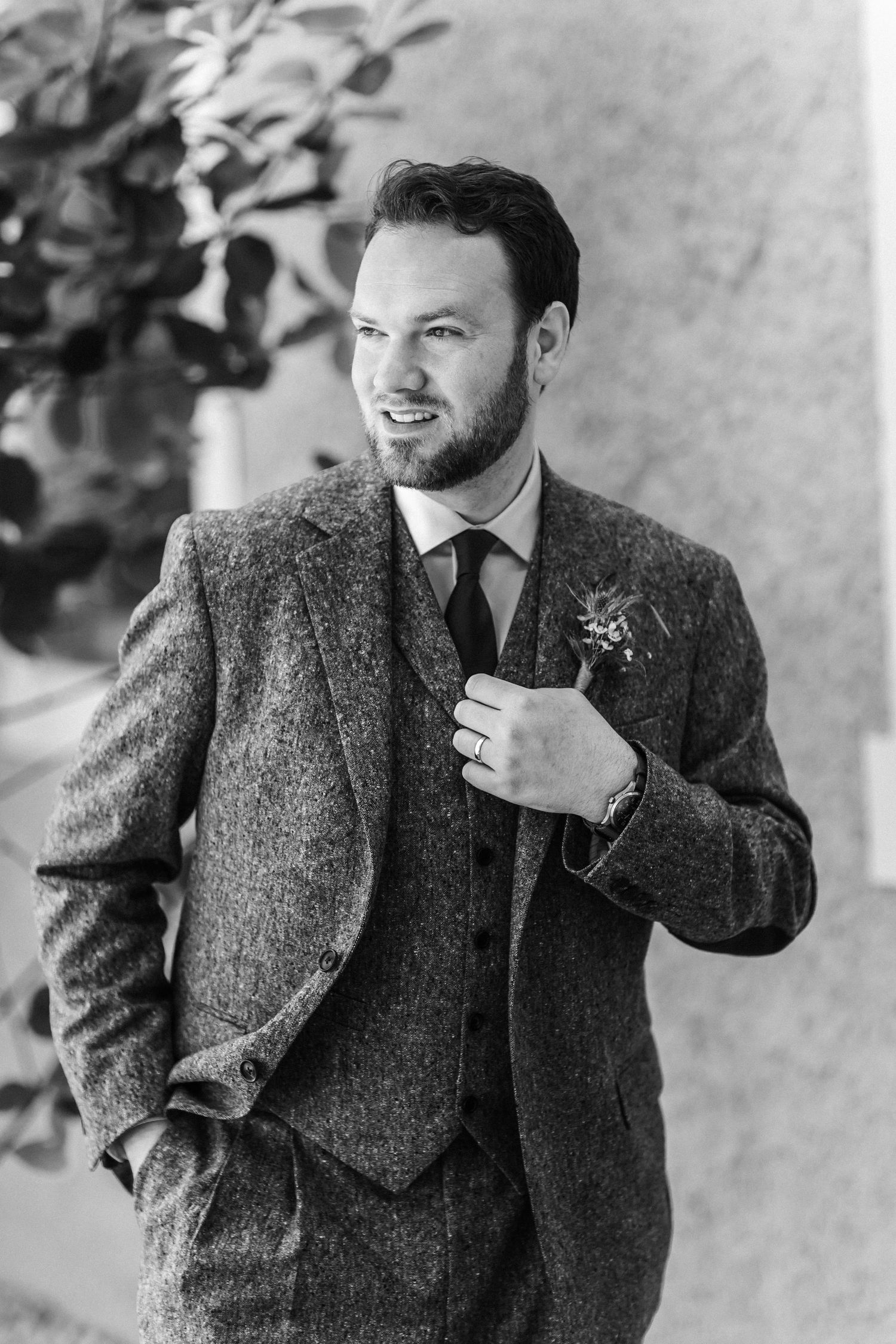 A groom adjusts his tweed suit jacket while getting ready for the wedding ceremony.
