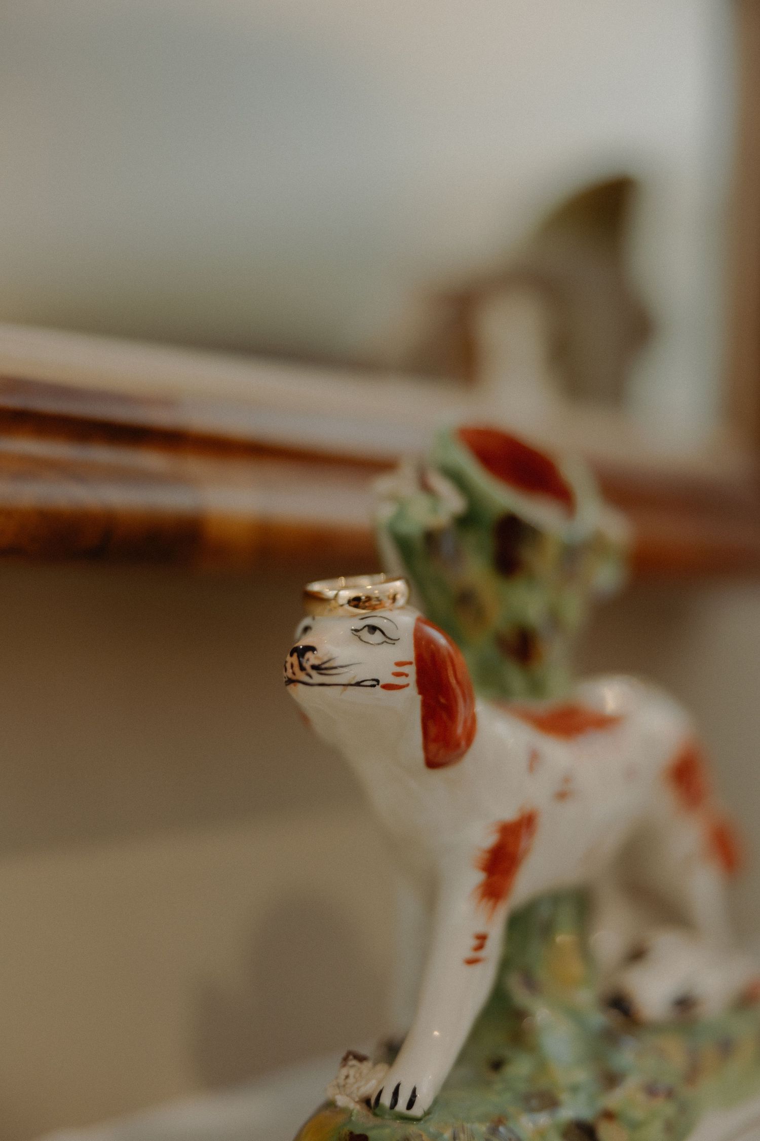 A row of small ceramic frog figurines sitting on a shelf with blurred background and warm lighting.