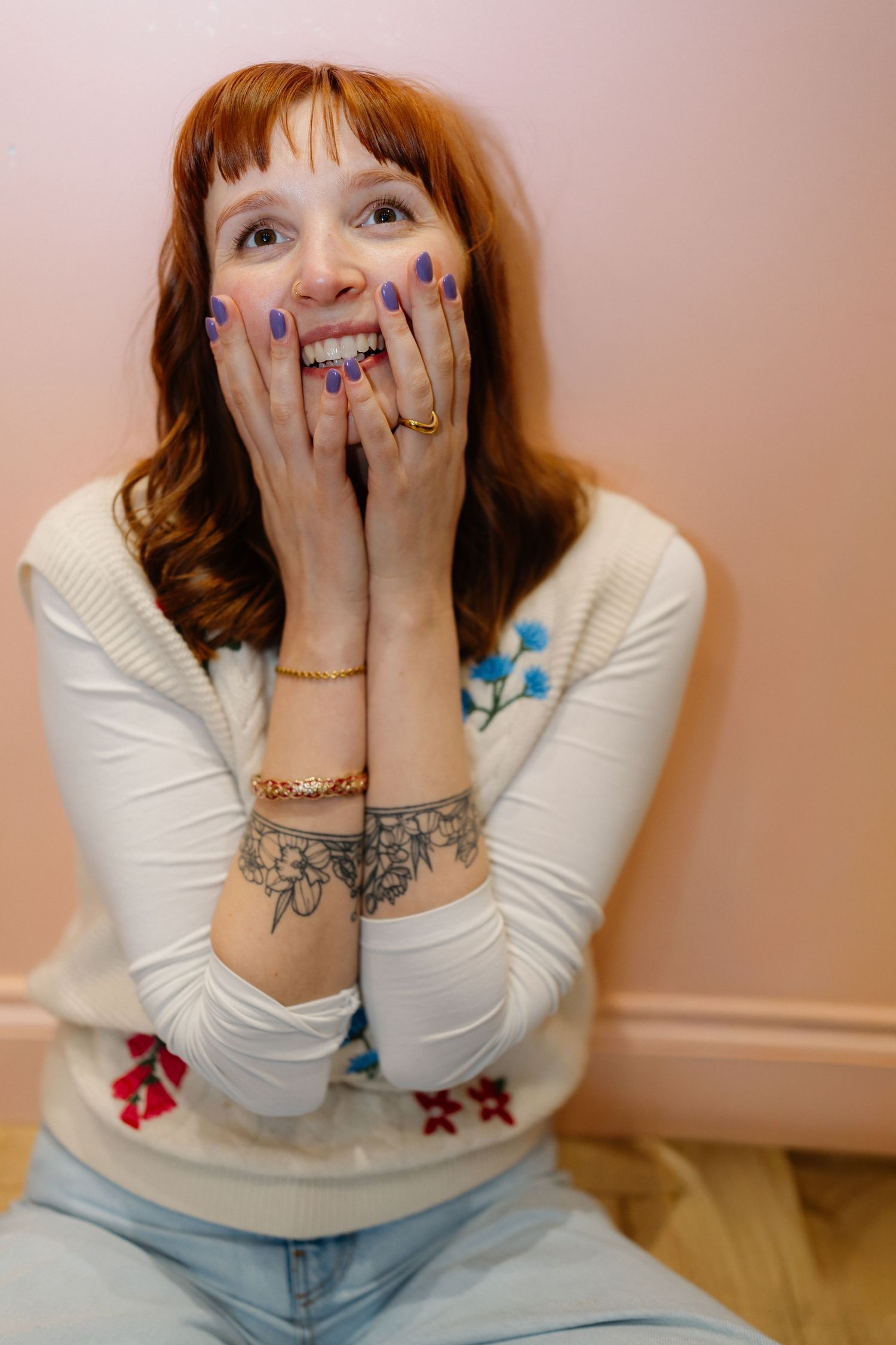 Person in white sweater showing playful expressions while wearing colorful nail polish.