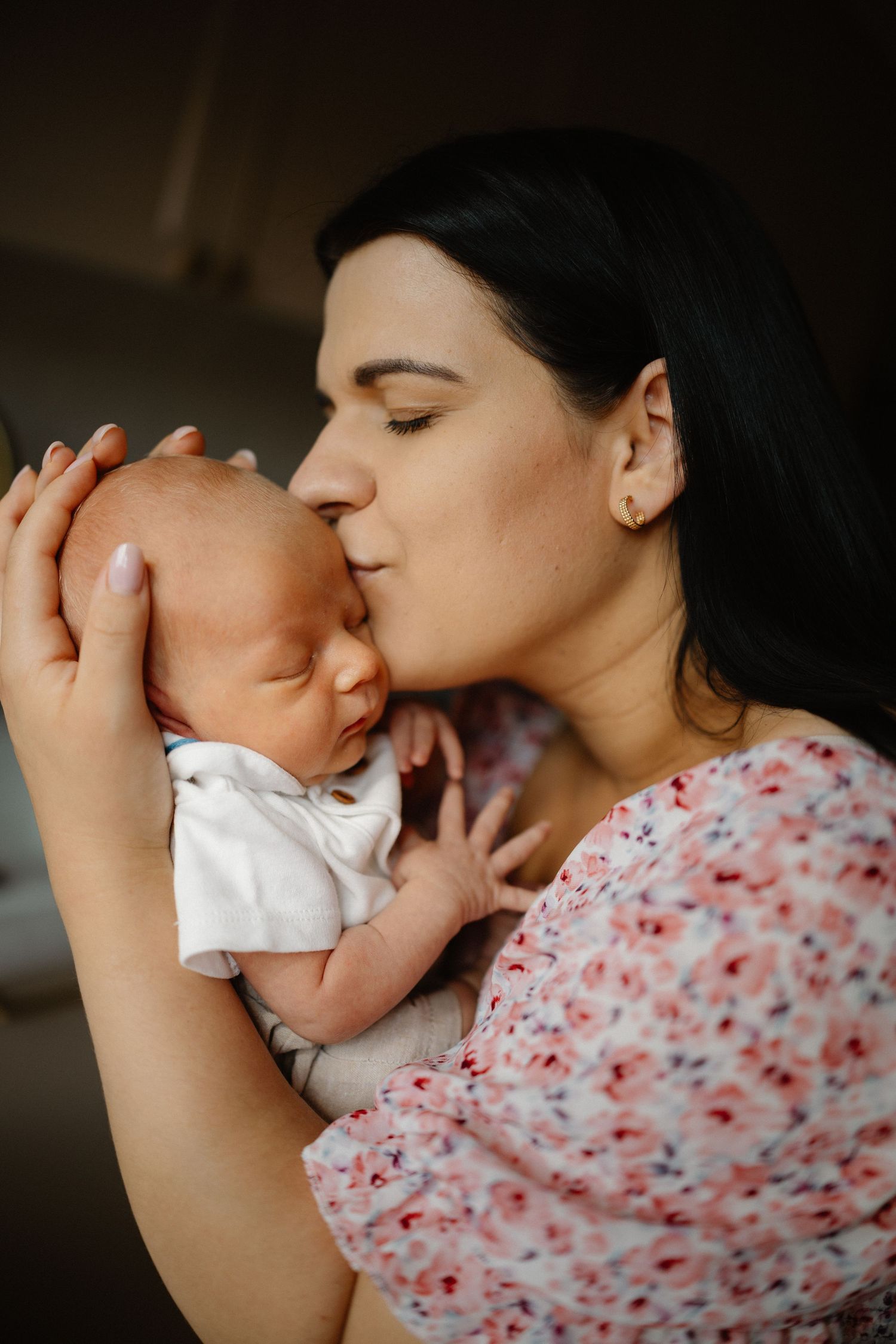 Sweet bonding moments with a baby wearing white against dark background.