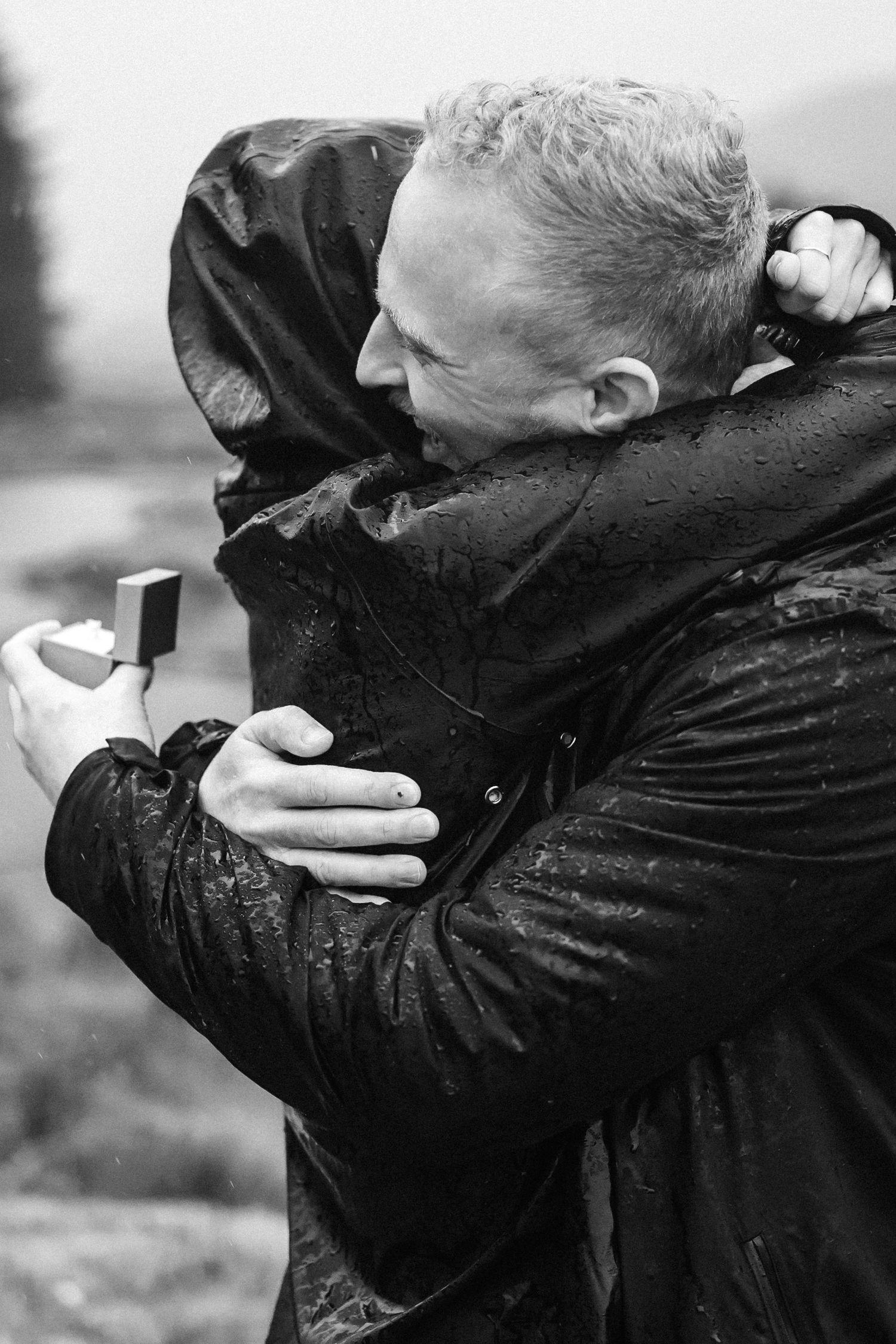 An emotional embrace captured in black and white on a rainy day.
