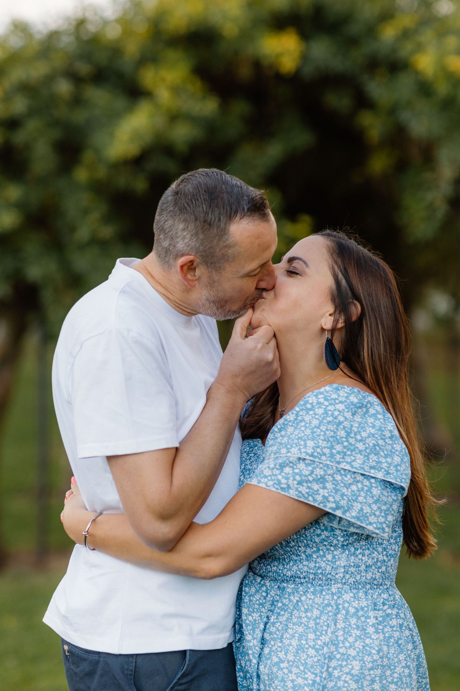 Romantic couple sharing intimate moments in a garden setting during sunset.