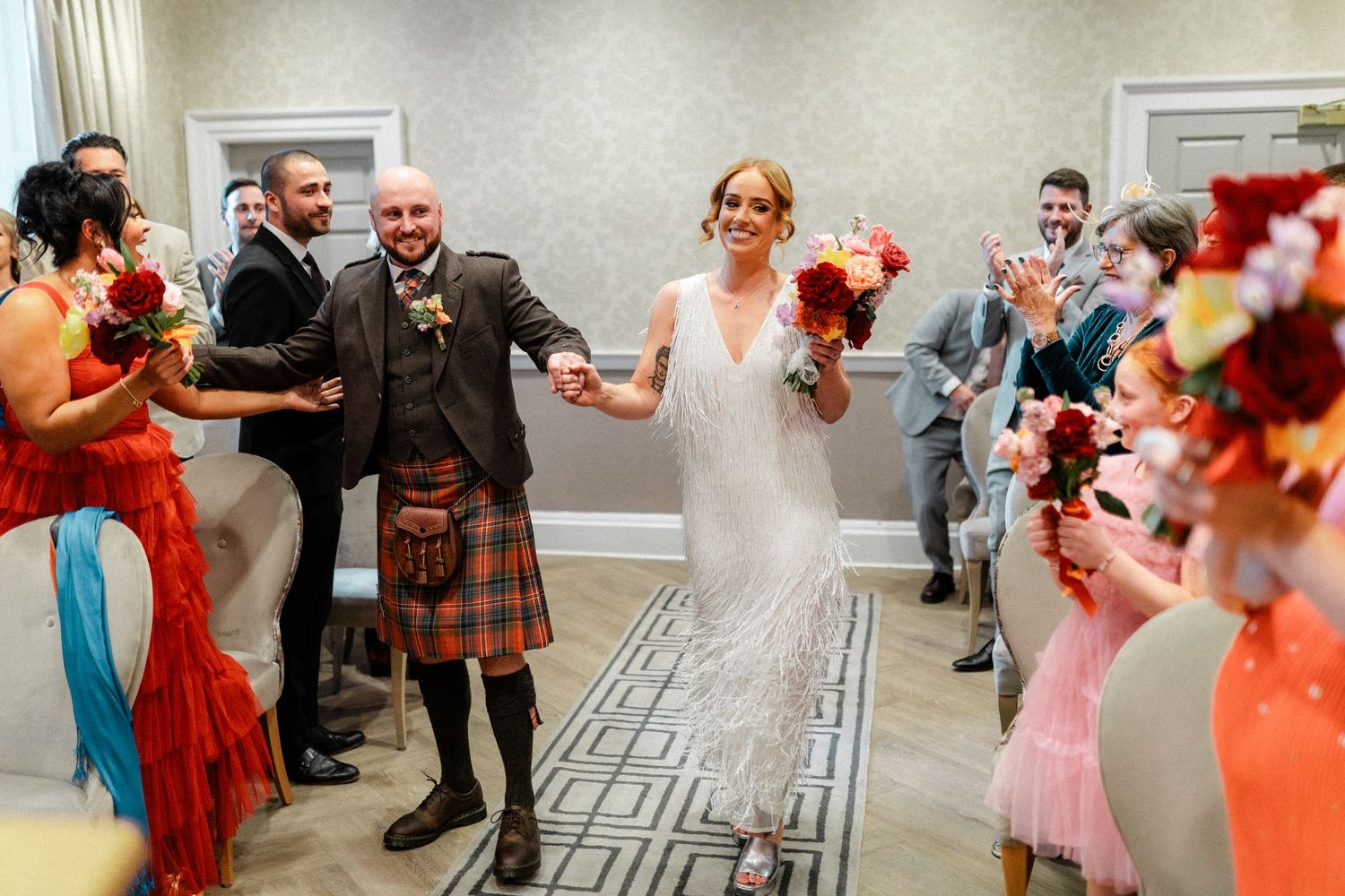 Bride and groom walk down the aisle in a wedding ceremony, groom wearing a tartan kilt.