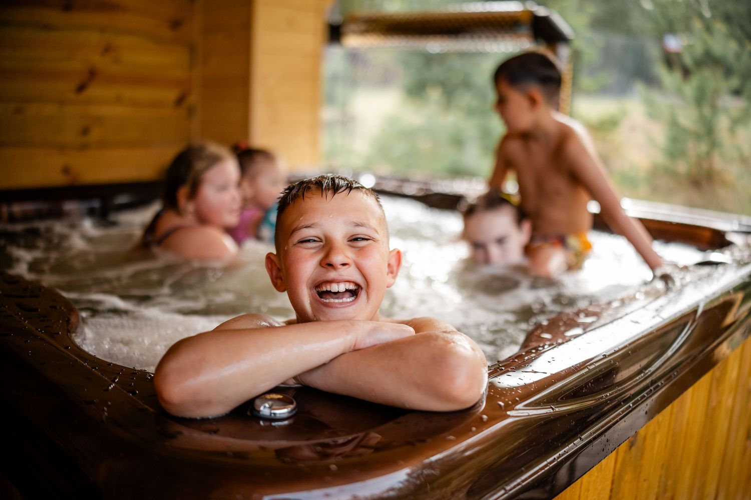 Children play and laugh in a rustic wooden bathtub during a lifestyle photo session.