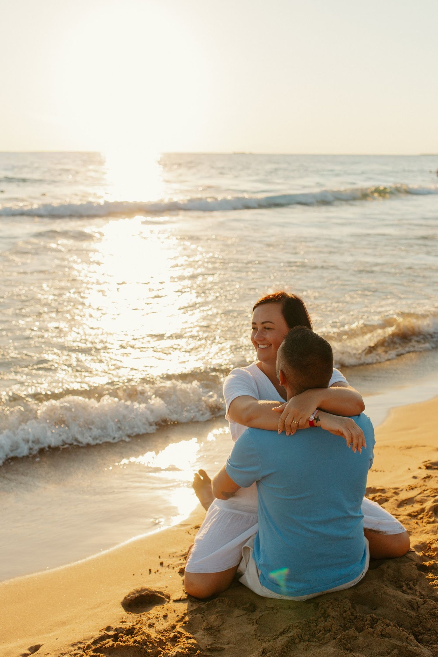 Couple sits together watching sunset on a peaceful beach.