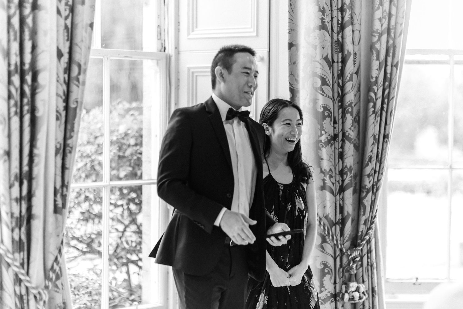Black and white photo of wedding guests mingling in an elegant reception room.
