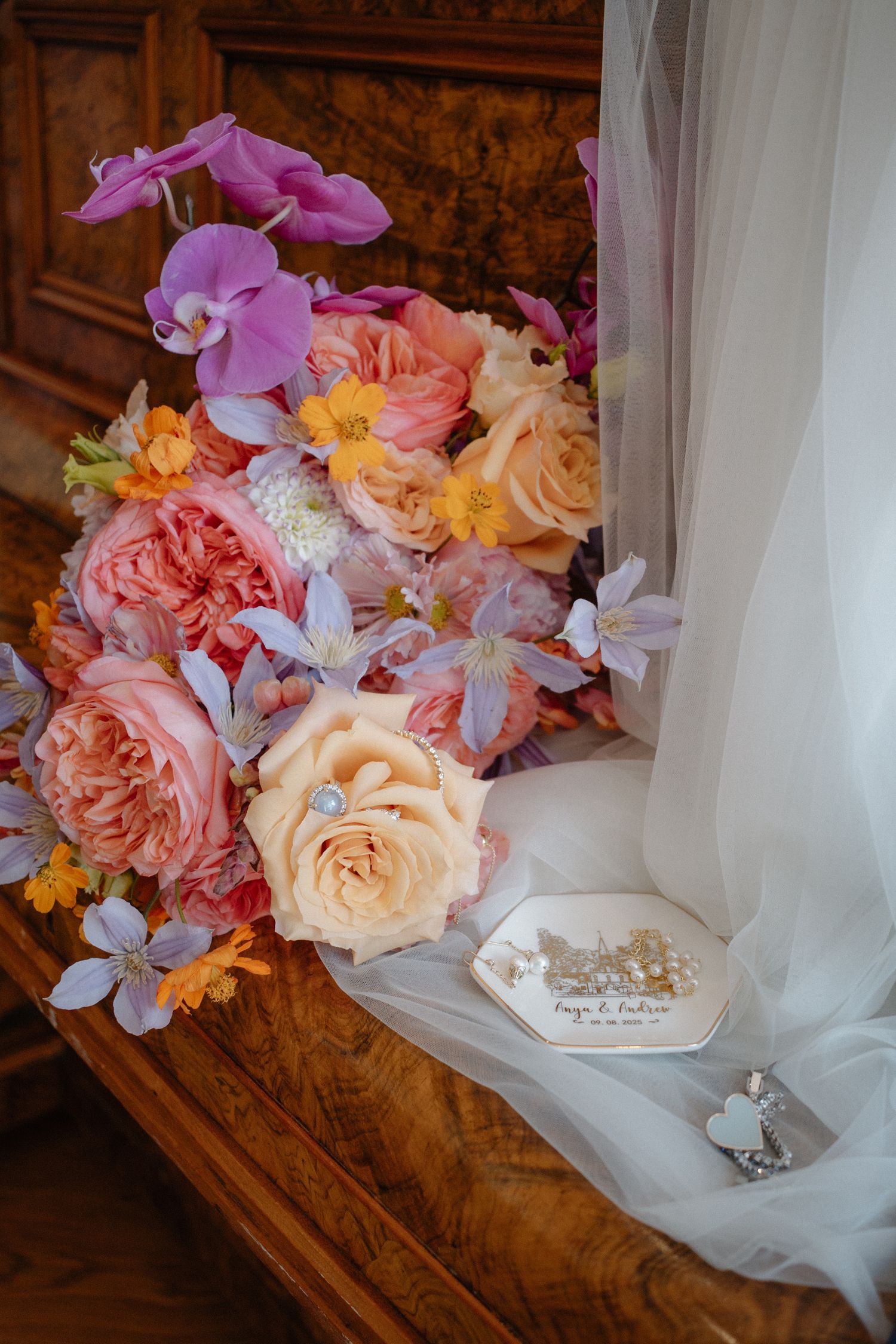 Delicate bridal bouquet with pink and peach roses alongside wedding veil and accessories.