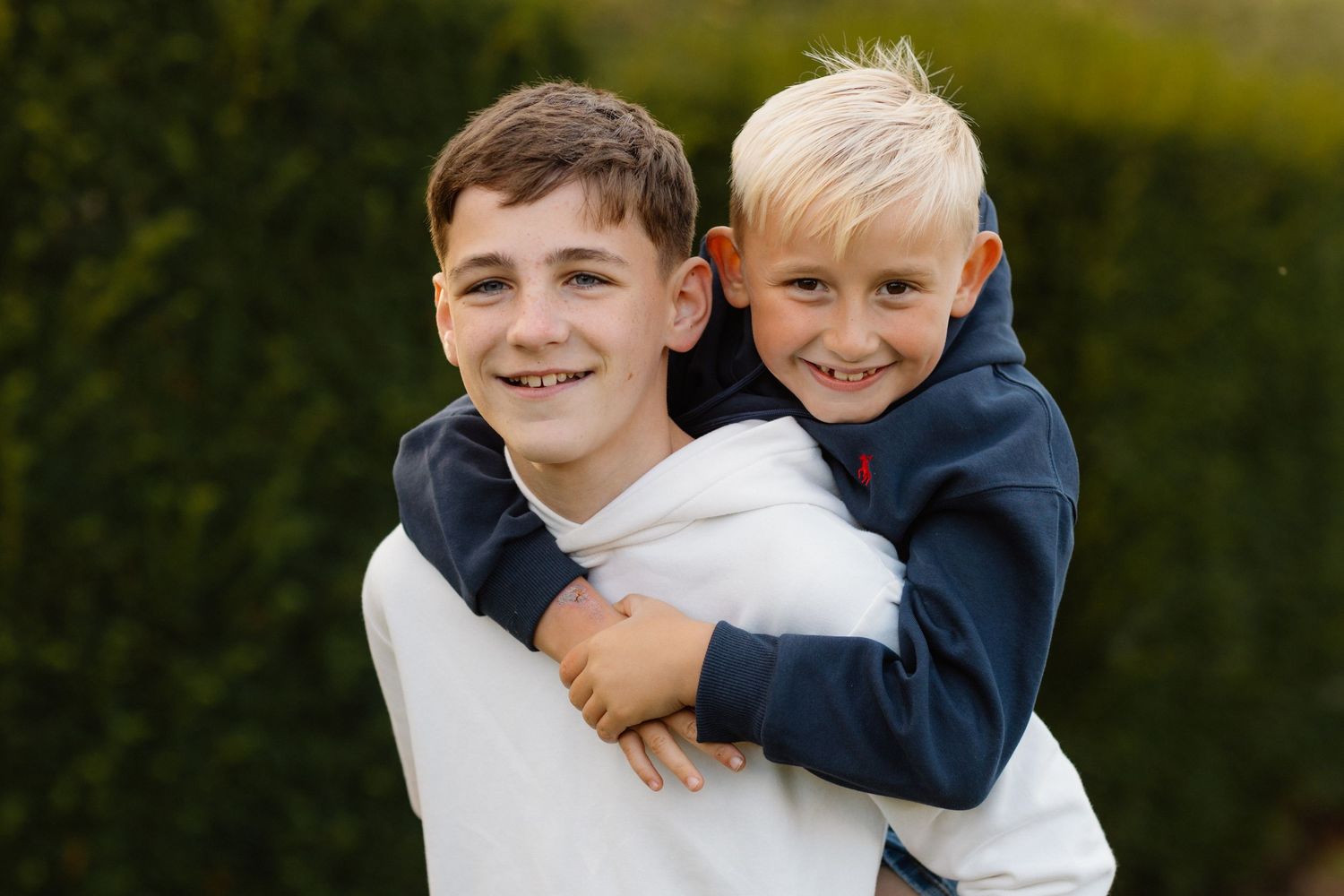 Two young boys sharing playful piggyback ride outdoors.