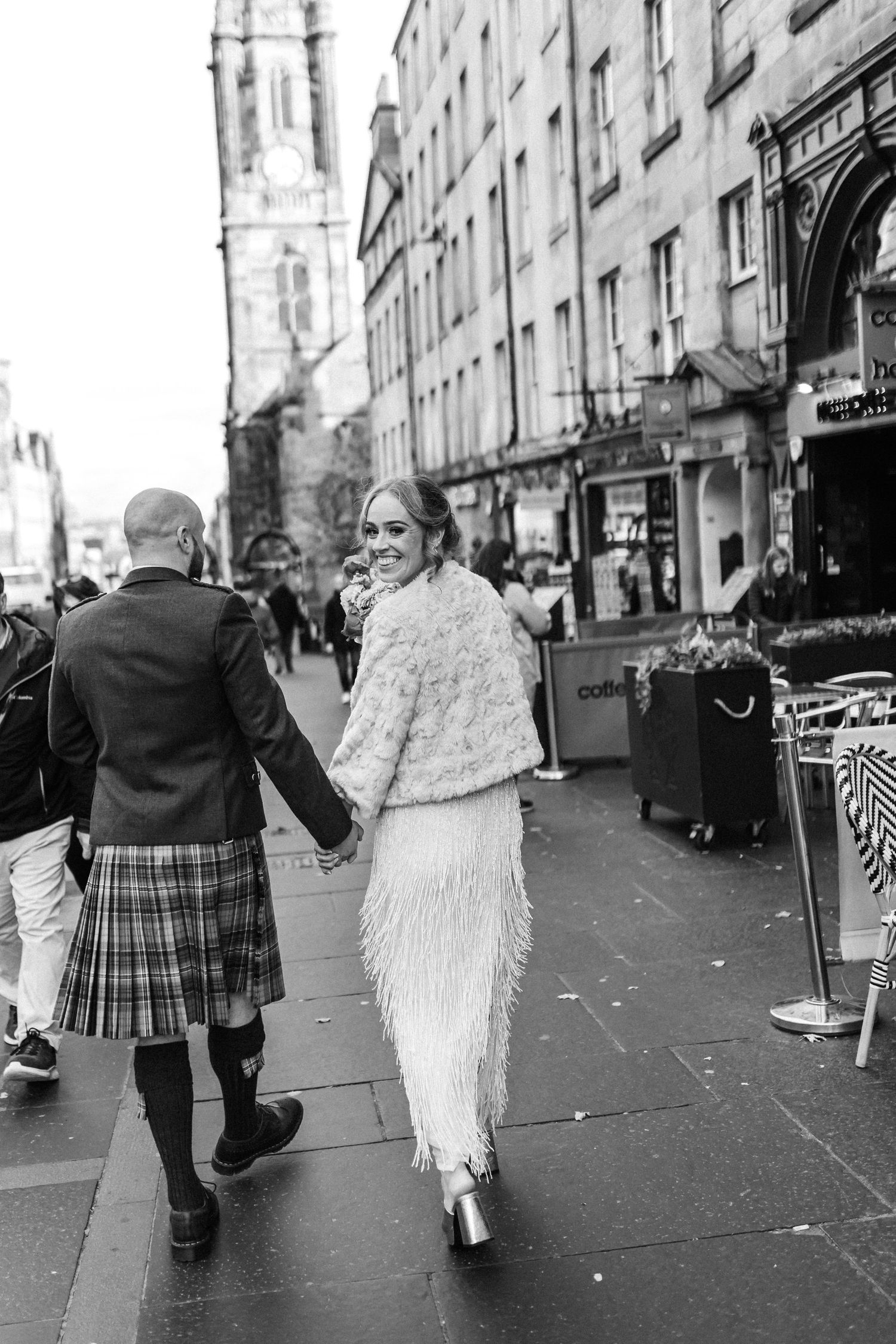 Candid black and white shots of couple walking along historic Edinburgh street after ceremony.