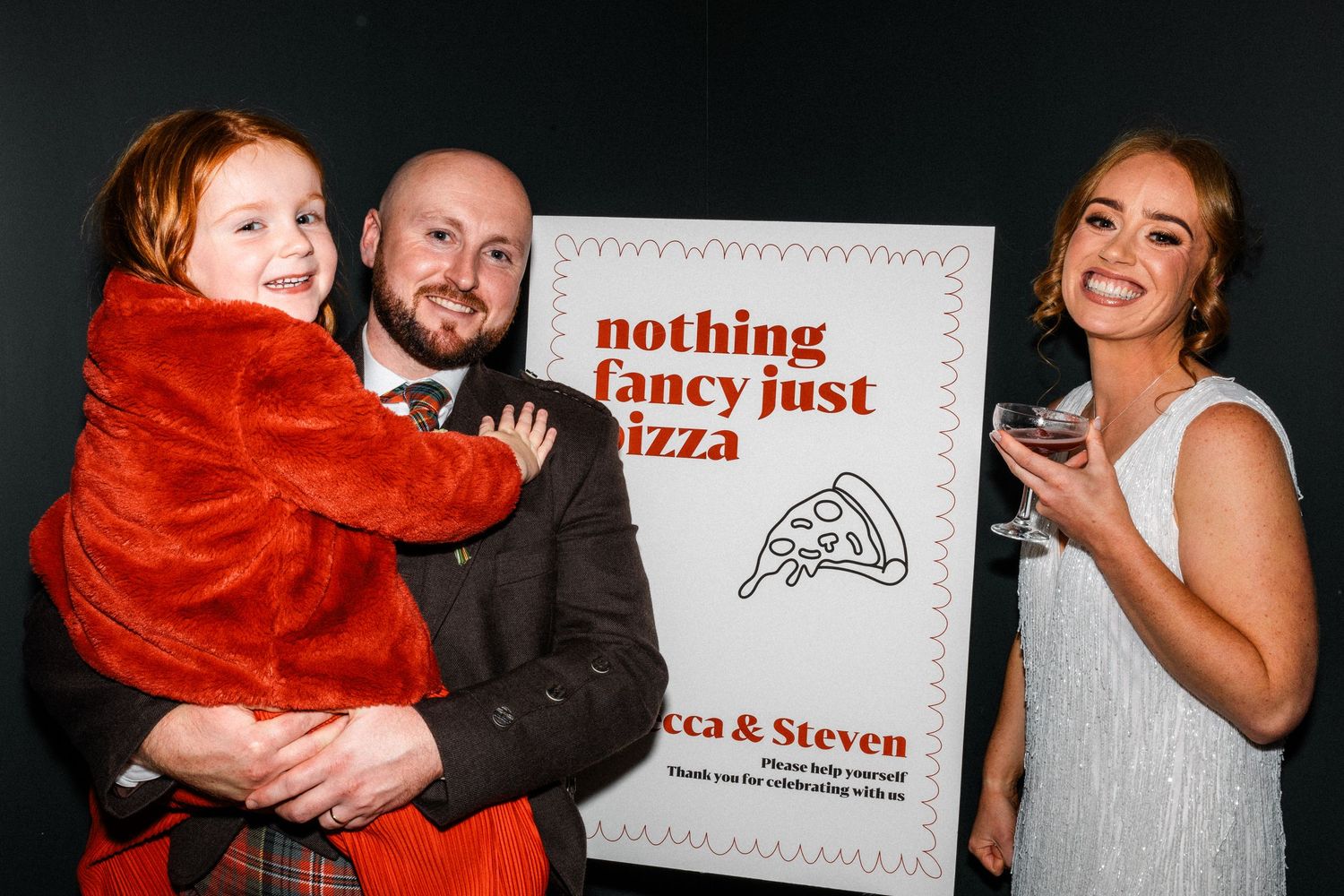 Wedding celebration with guests dancing and having fun near a pizza-themed sign.