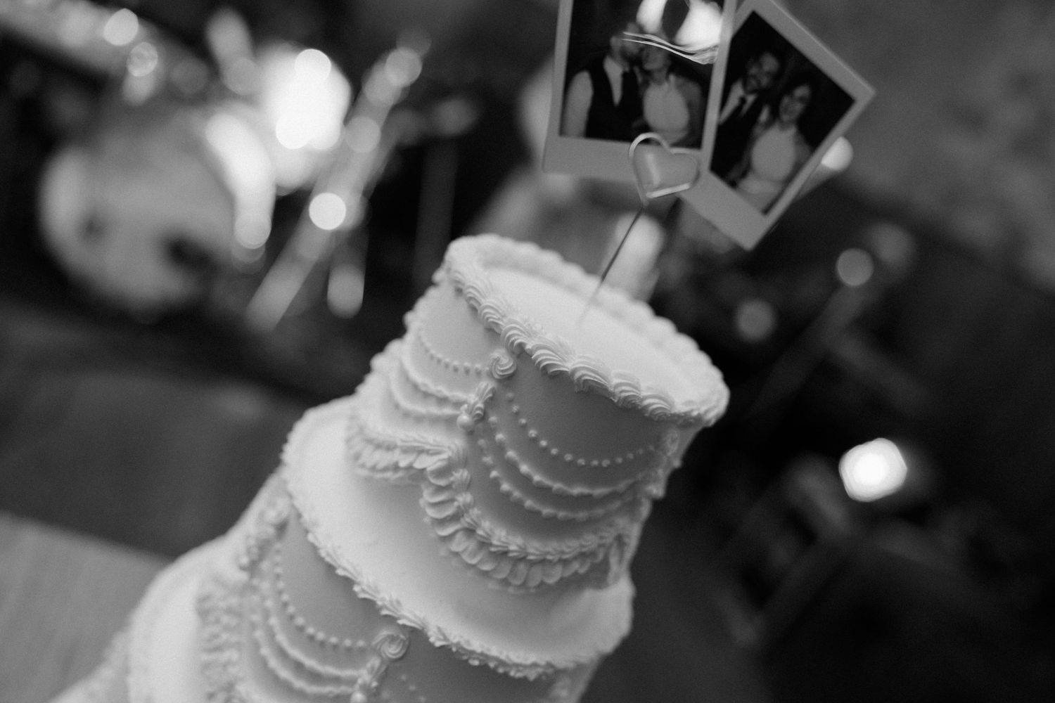Elegant white wedding cake with delicate pearl details photographed in black and white.