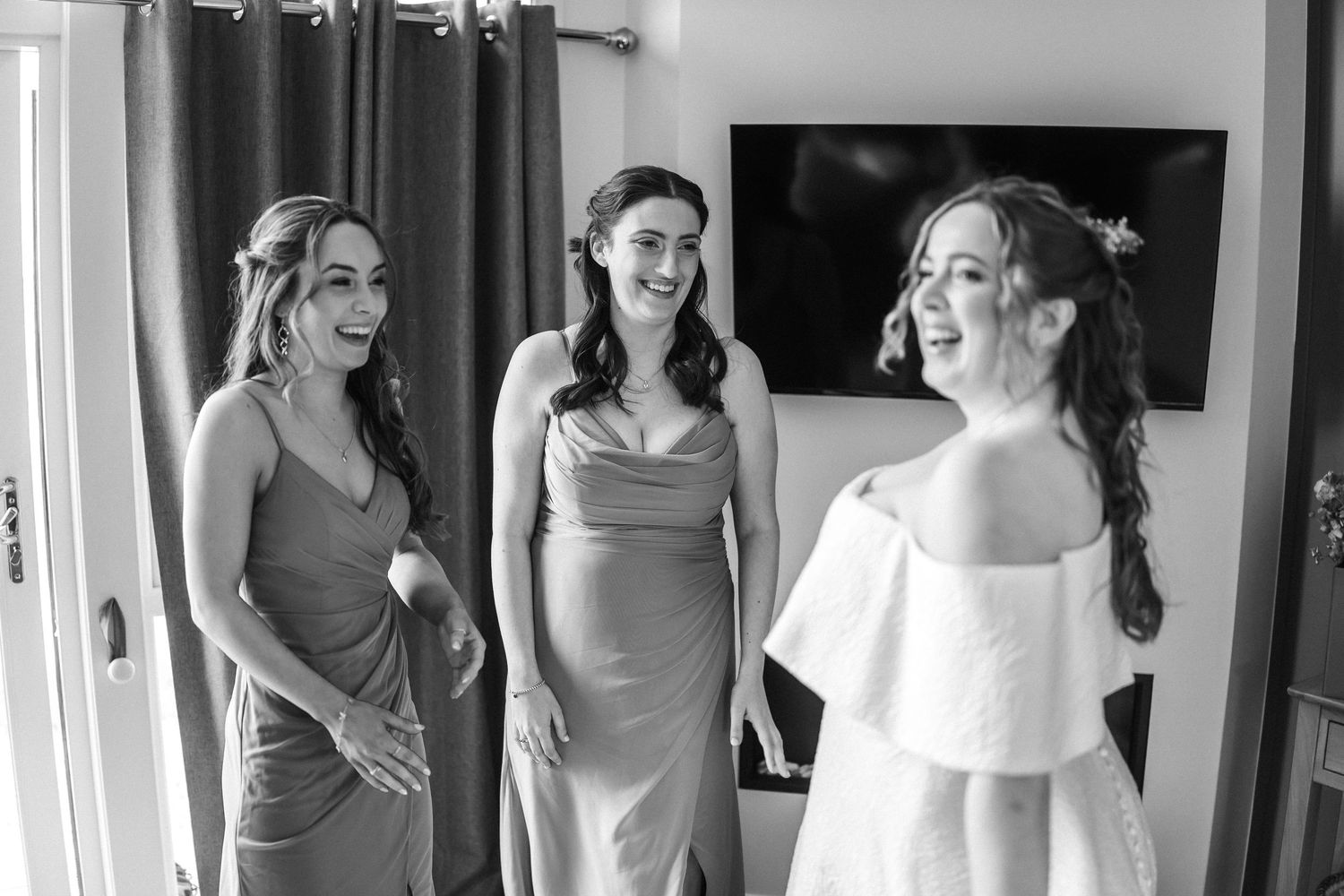 Interior getting ready scene with white and grey dresses visible.