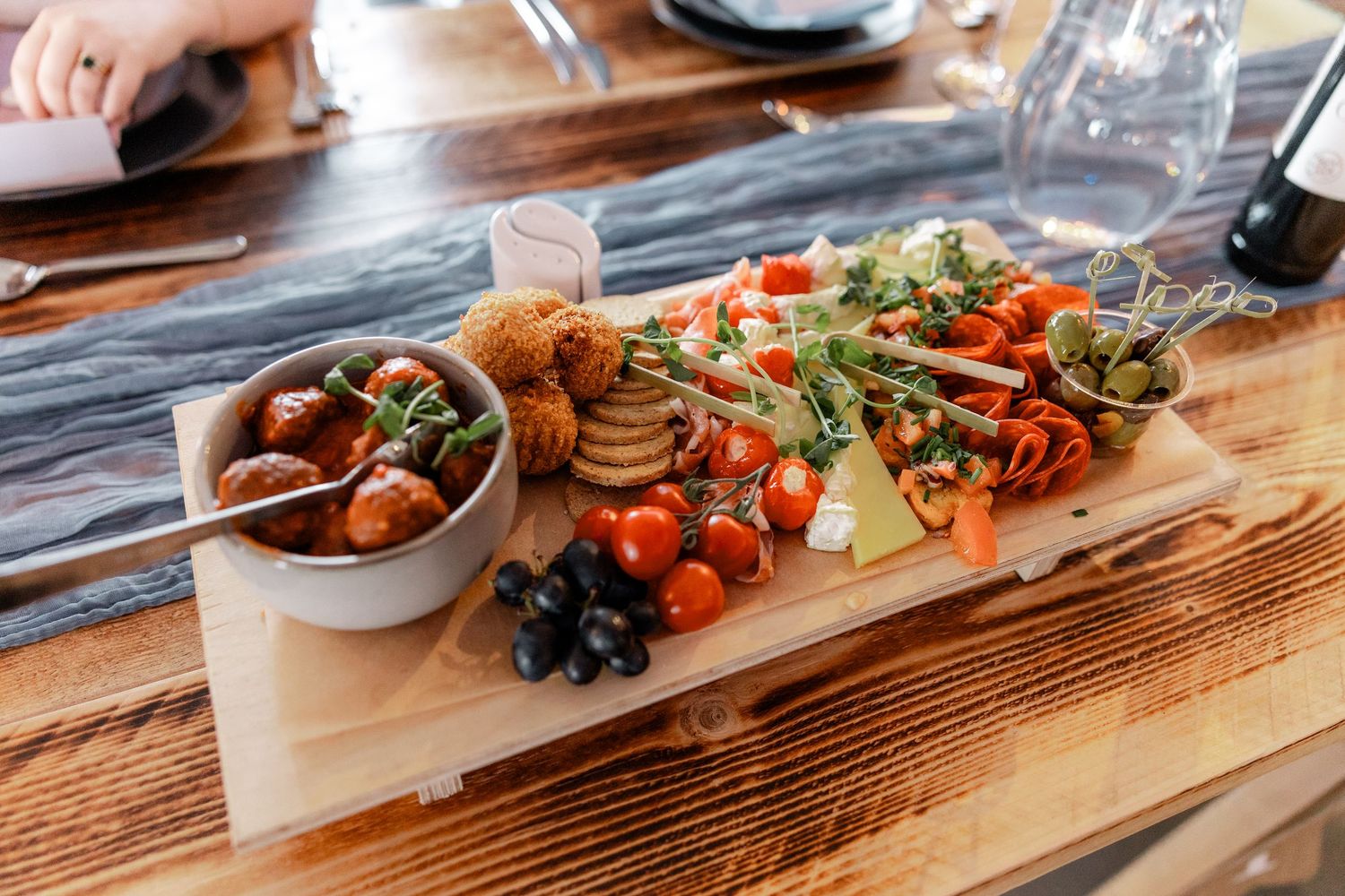 Wooden charcuterie board with assorted appetizers and snacks at an event.