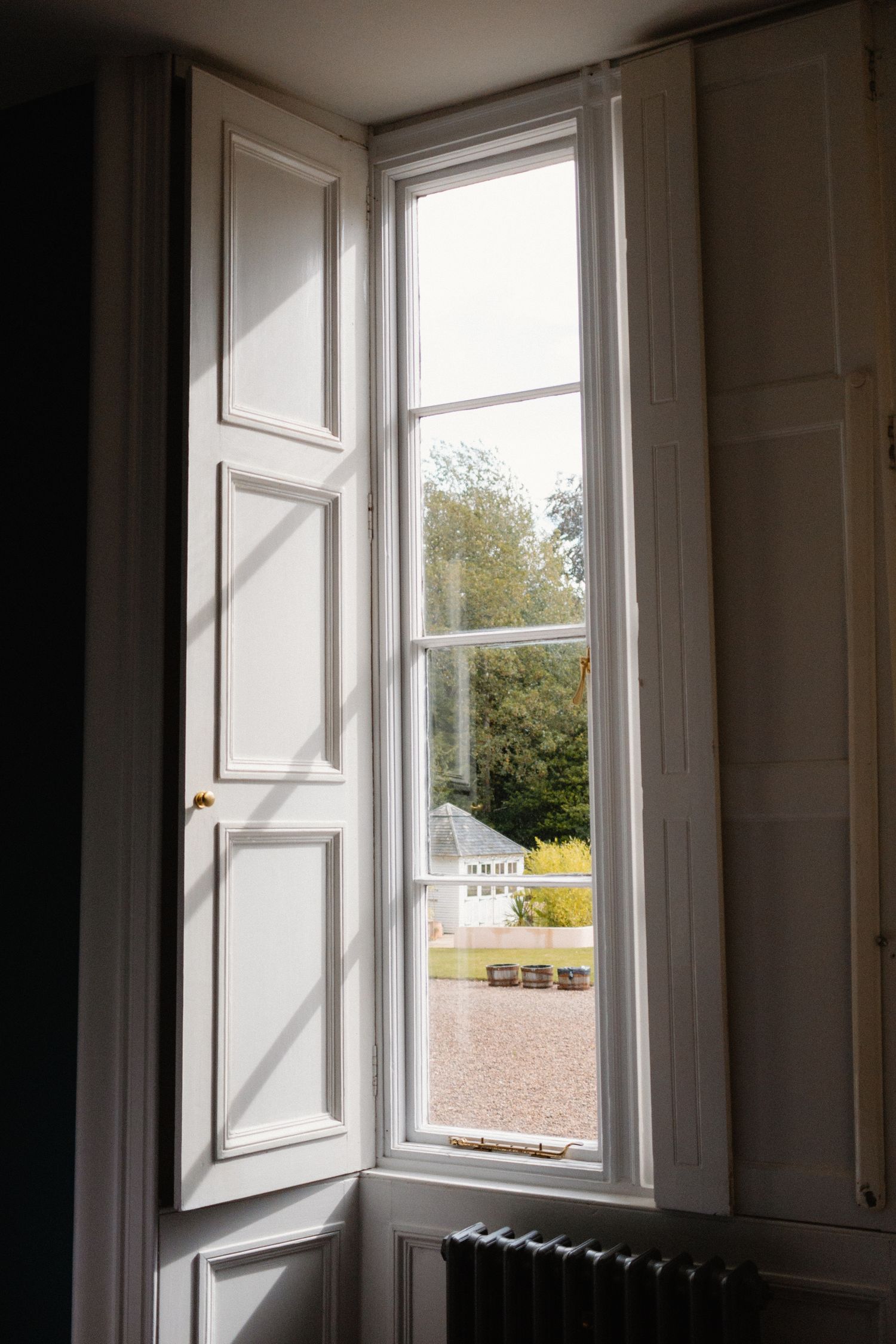 A series of open white windows in a room showing different views of trees and buildings outside.