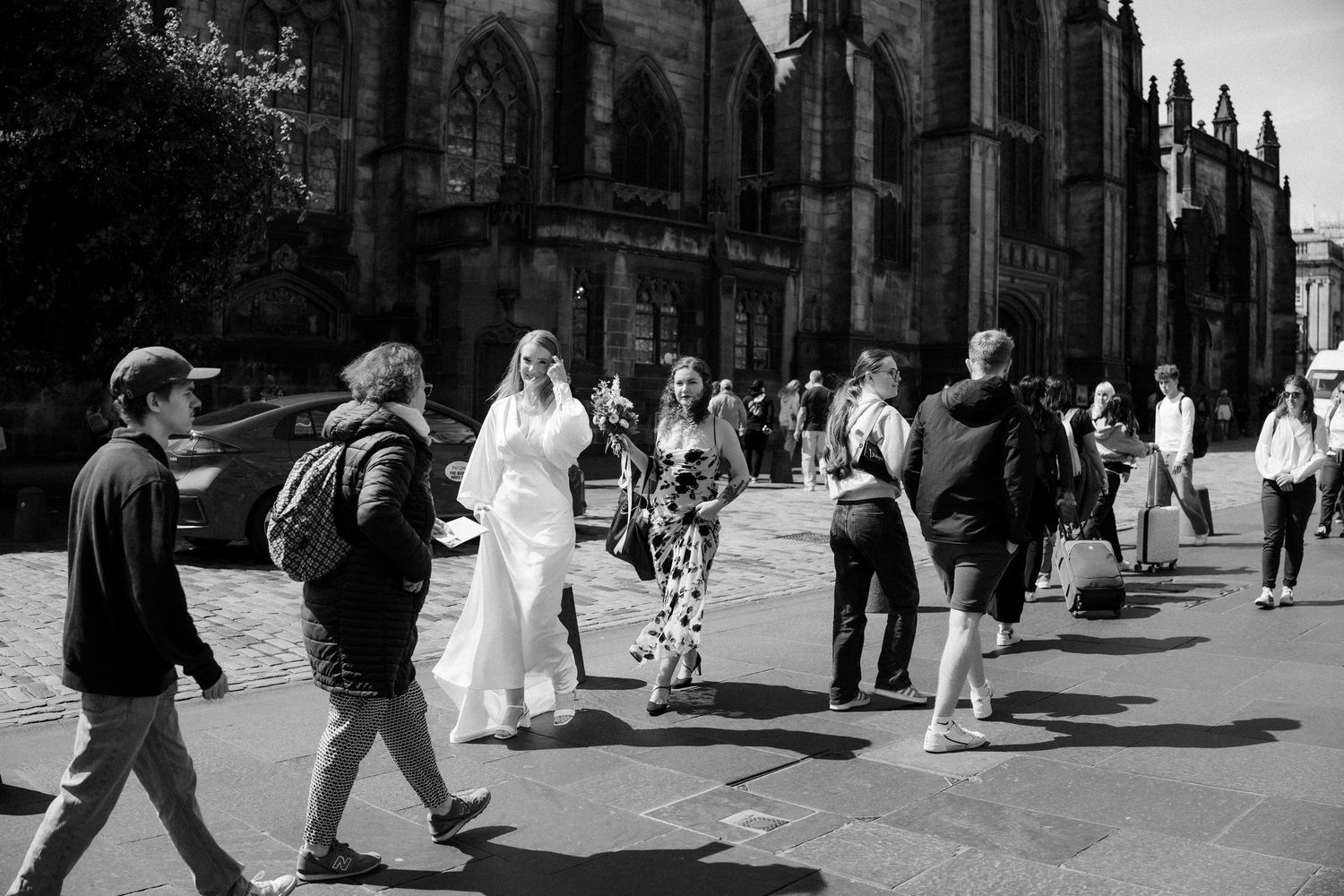 Black and white photo of bride in white dress walking near St Giles Cathedral on Royal Mile Edinburgh.