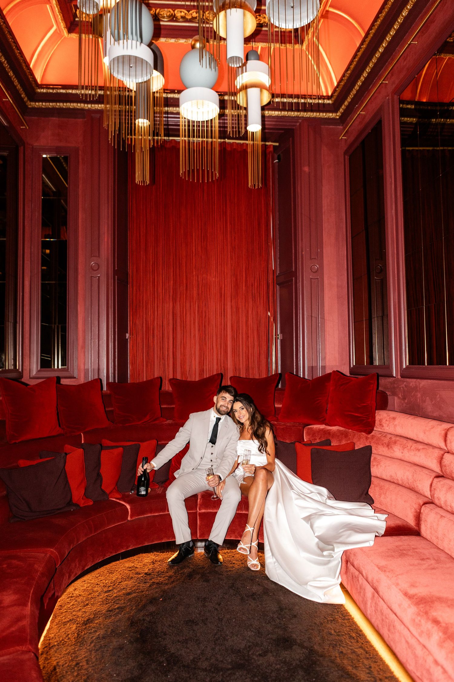 Romantic photo sequence in a luxurious red room with ornate lighting and plush seating.