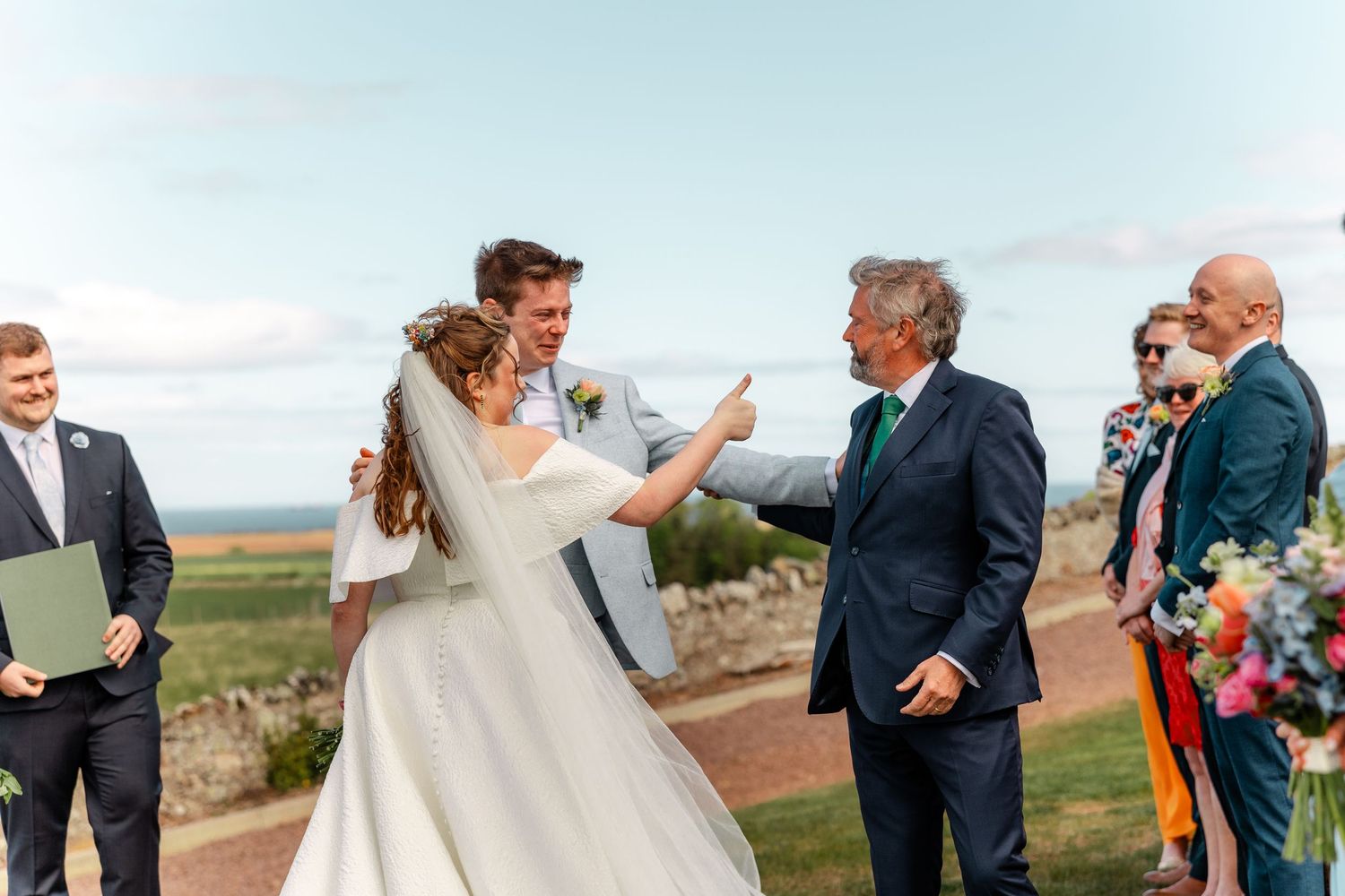 Wedding party poses for photos against a scenic mountain landscape.
