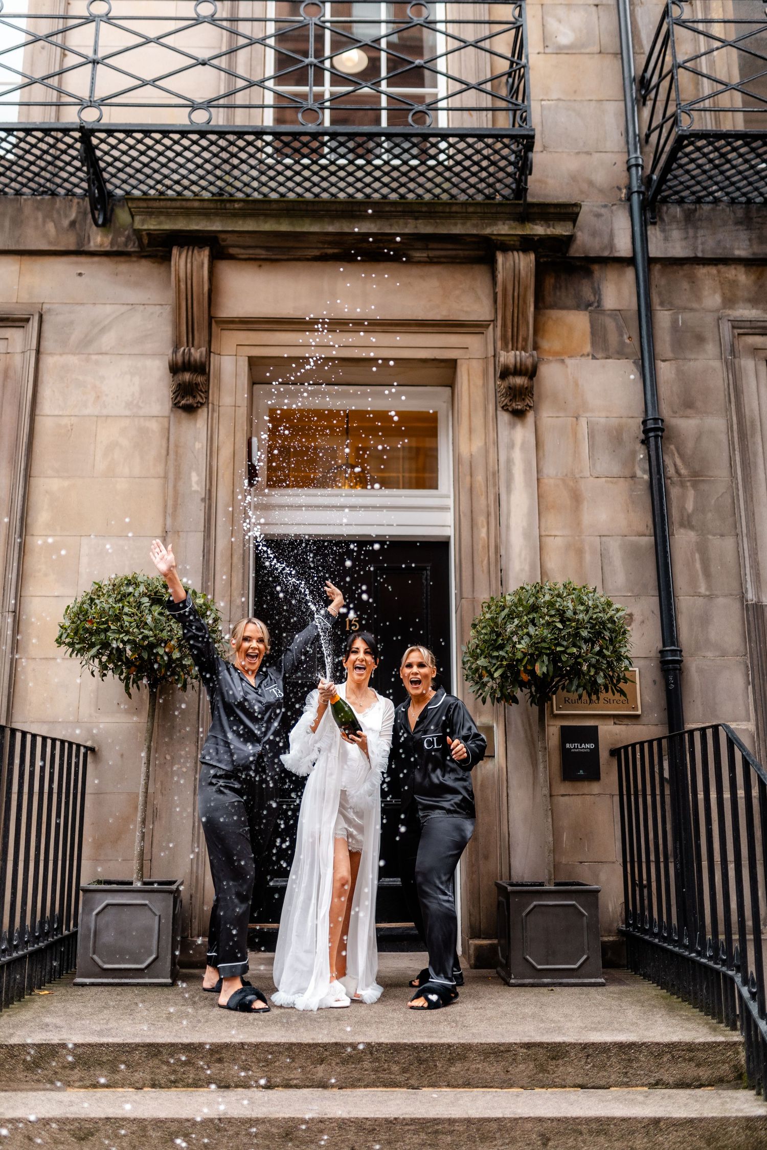 Wedding celebration outside stone building with confetti being thrown.