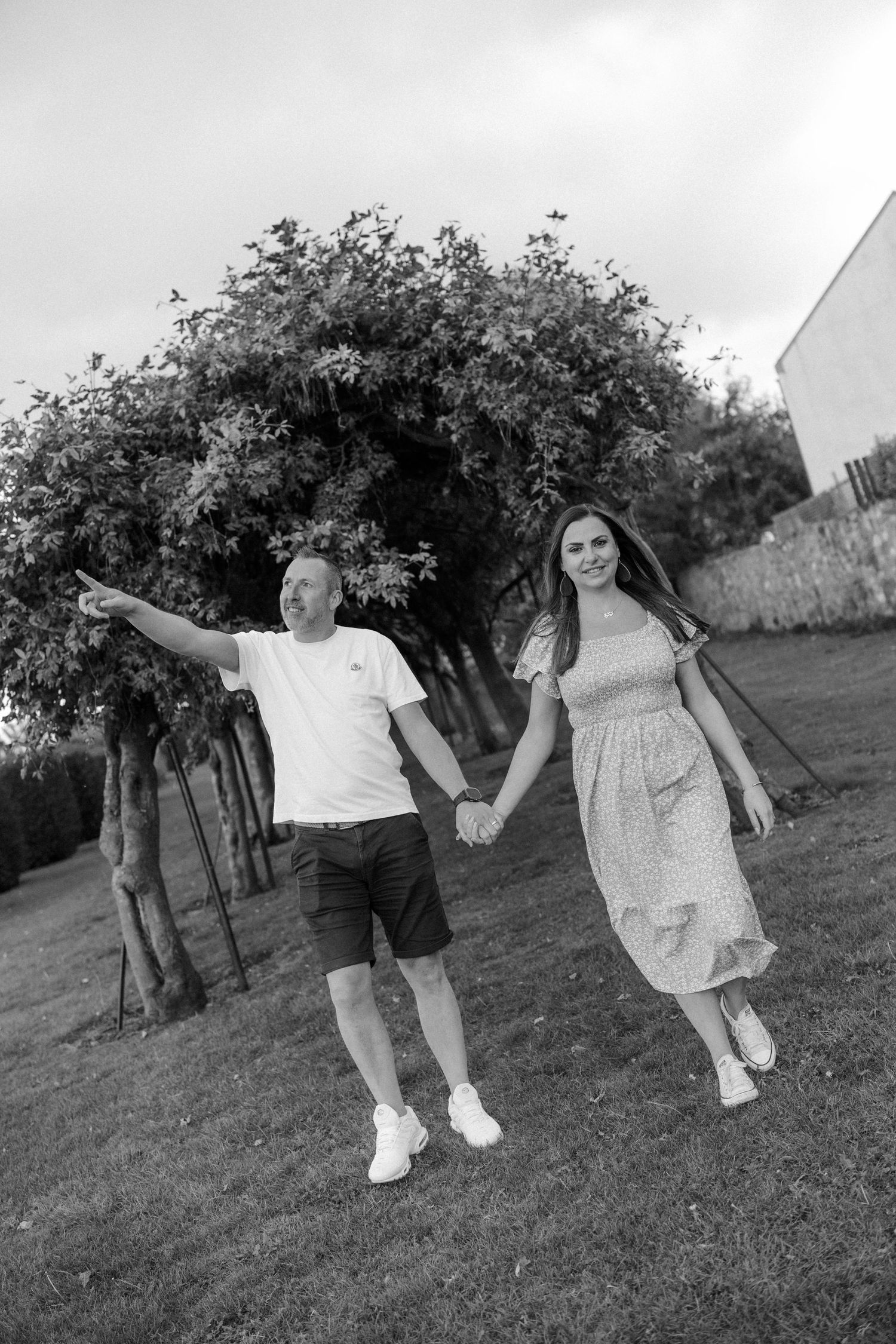 Black and white photo of couple walking and playing in an outdoor garden setting.