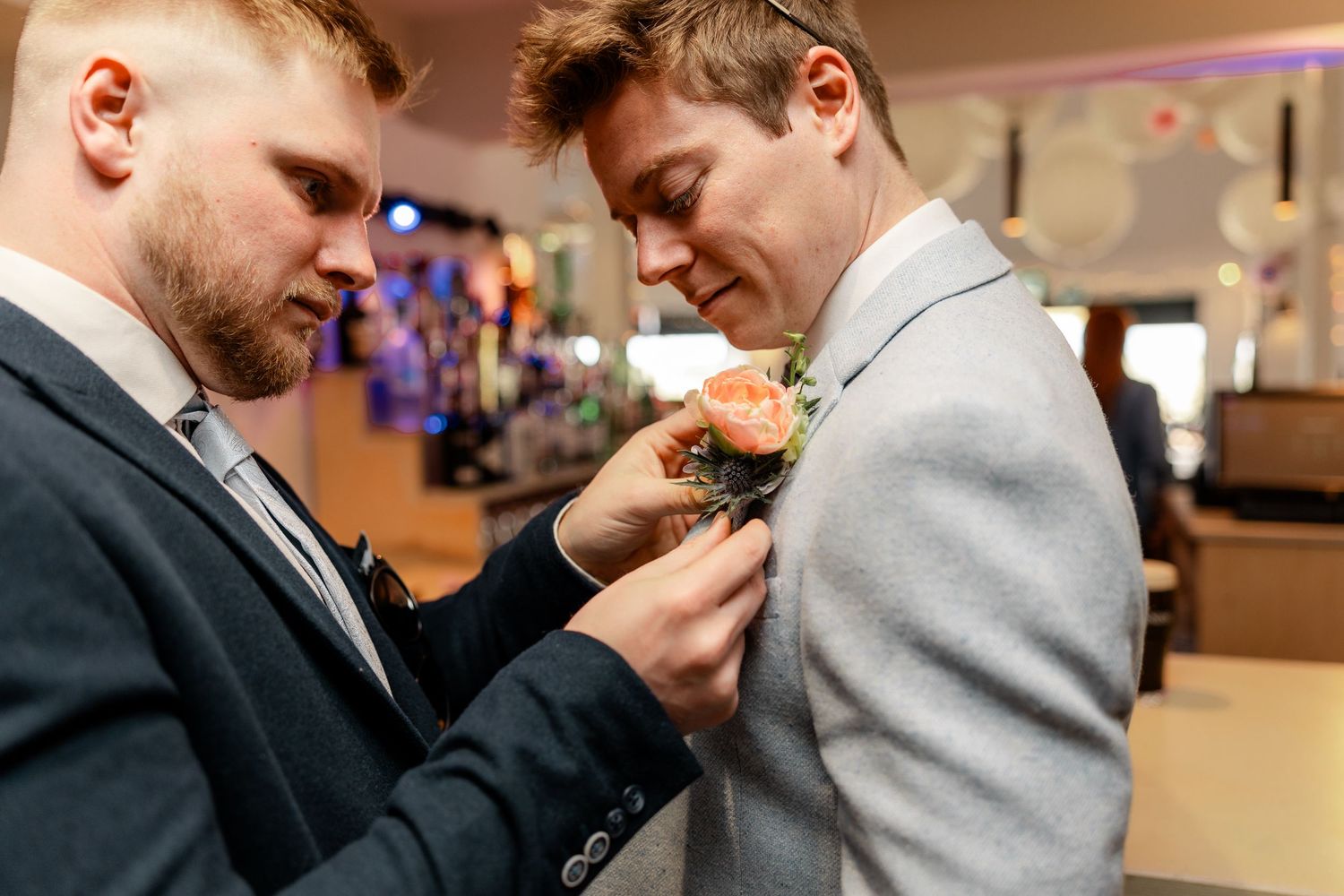 Groomsmen help adjust each other's ties and boutonnieres in a sequence of getting ready shots.