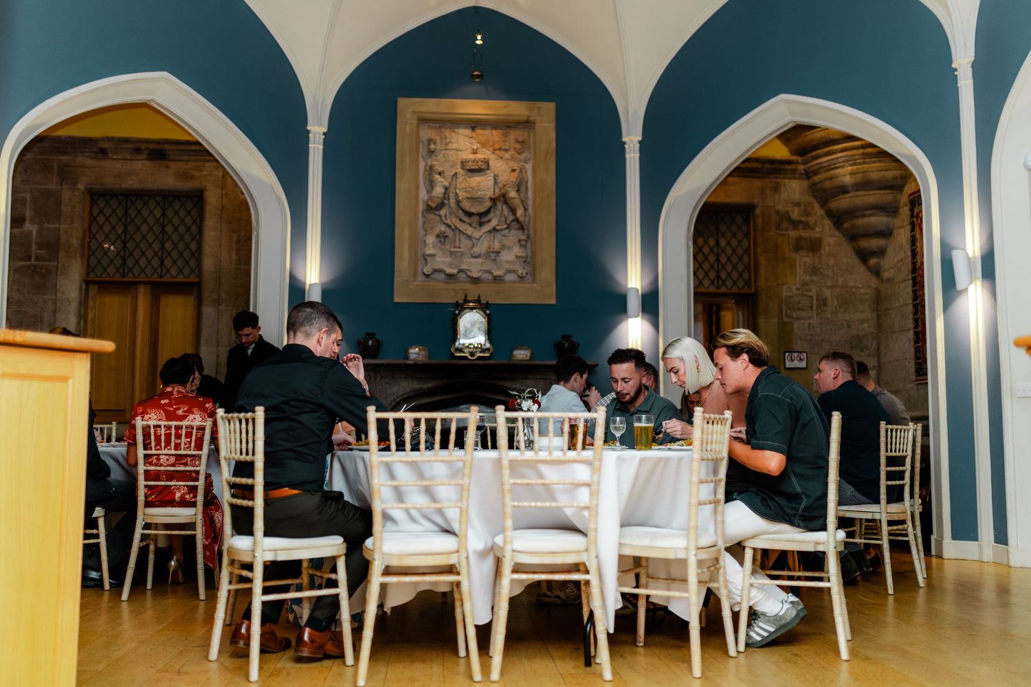 Formal dining space with arched doorways and white chairs under vaulted ceilings.