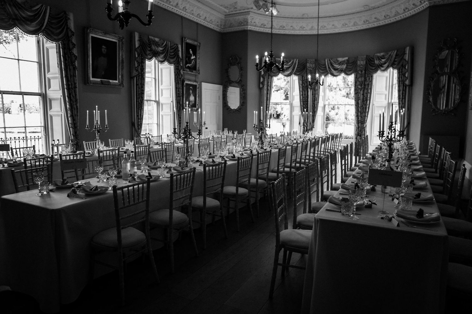 Elegant banquet hall setup with rows of tables and chairs in a grand room with ornate architectural details.