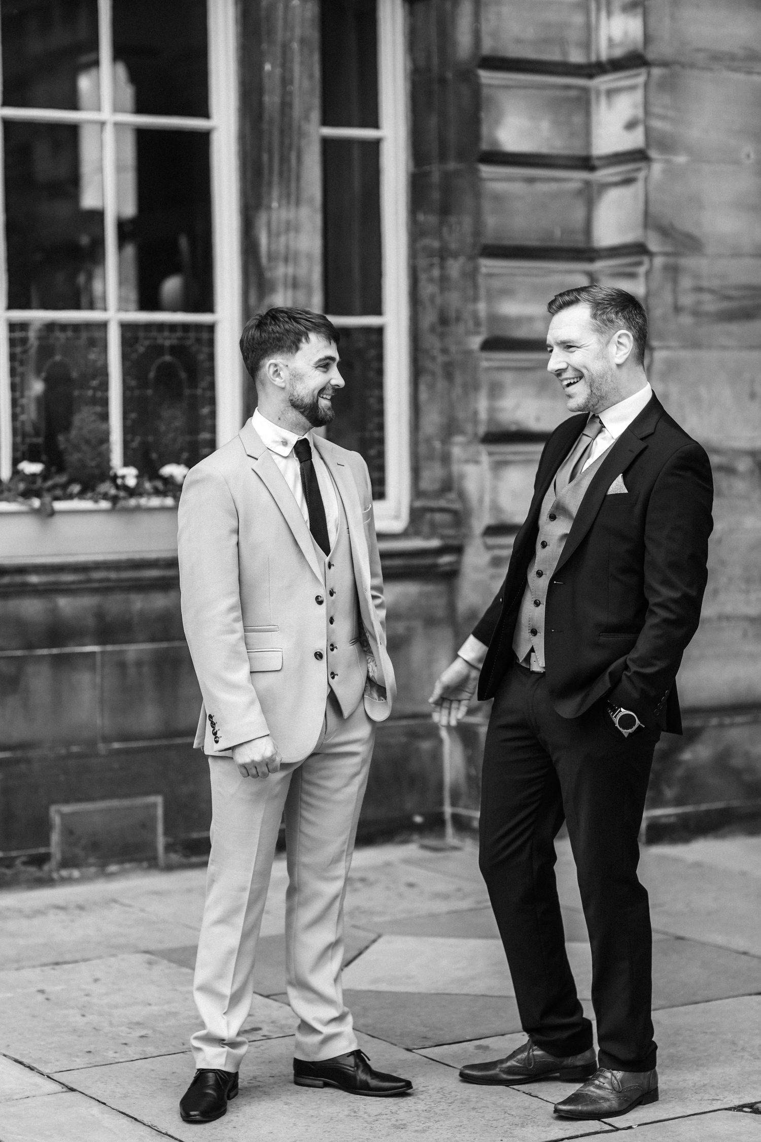Two people sharing a candid moment outside a historic Edinburgh building in black and white.
