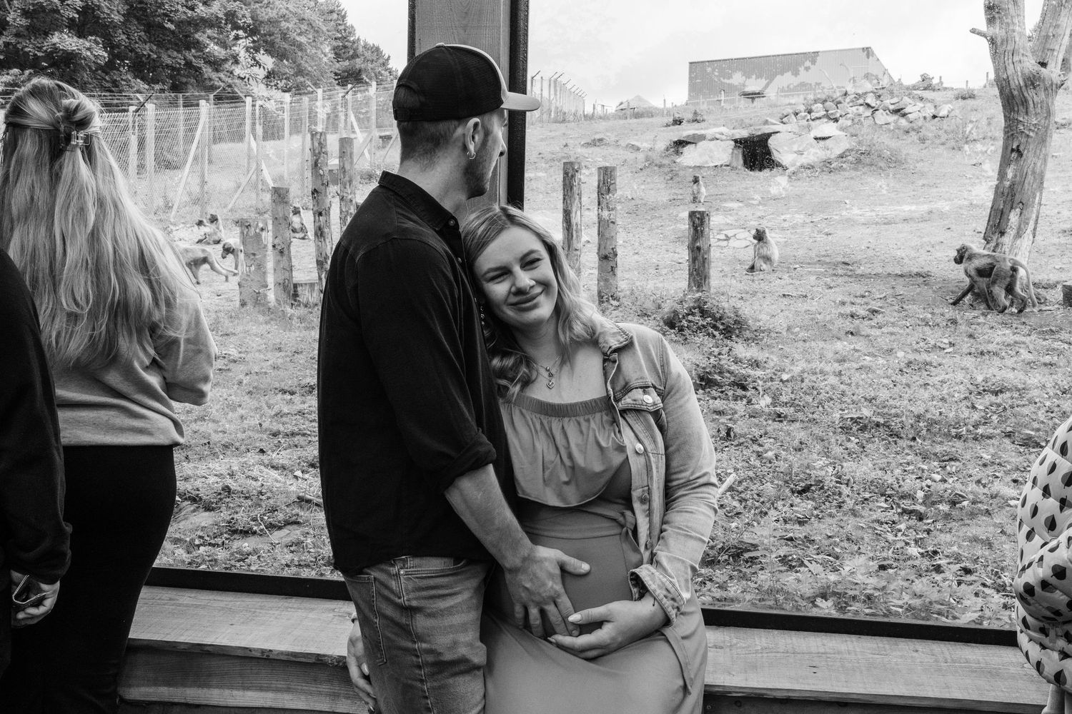 Black and white photo of couple embracing in rustic outdoor setting.