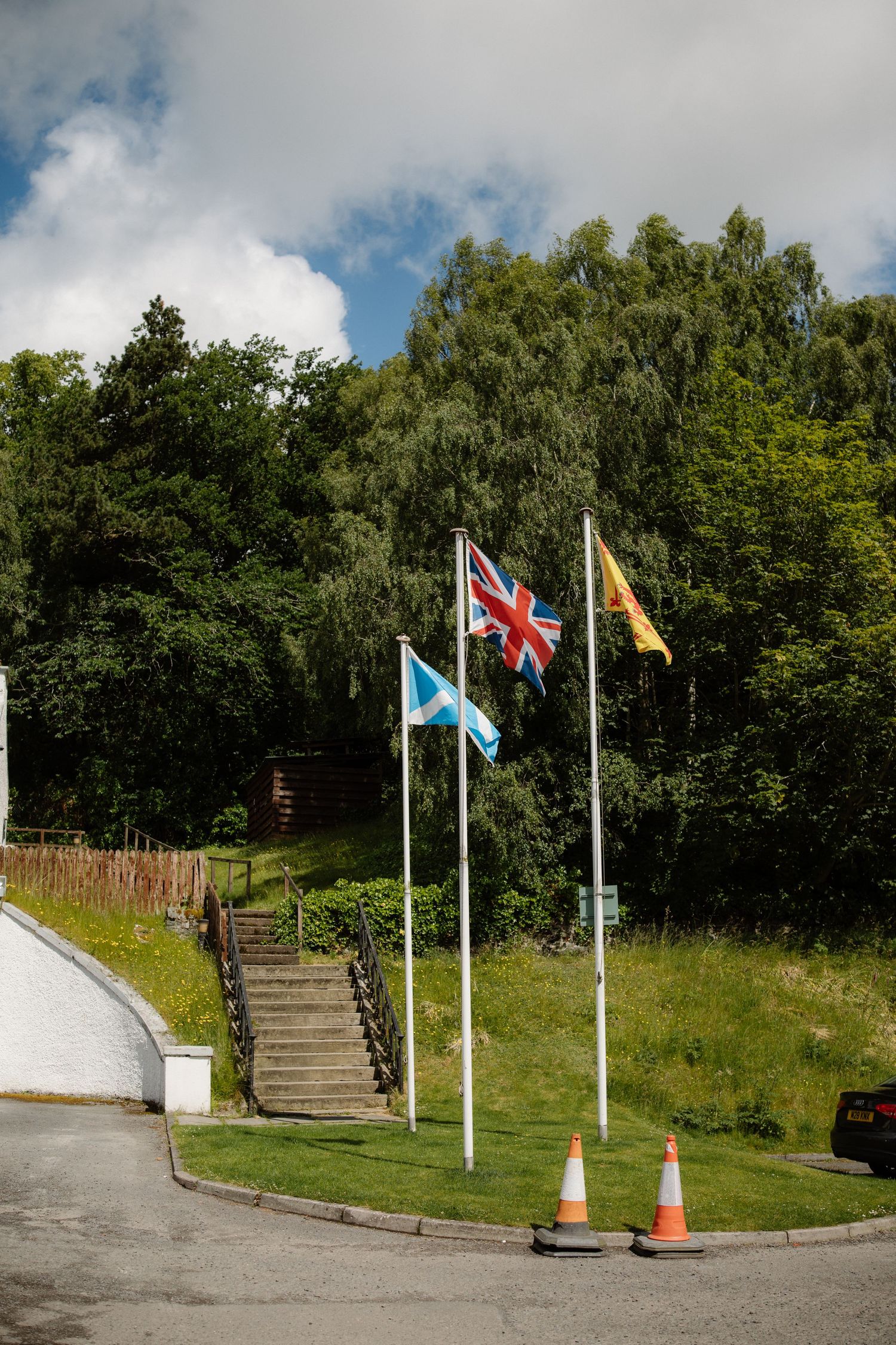 Scottish Saltire, Union Jack and Royal Standard flags flying on poles outside a Scottish wedding venue.