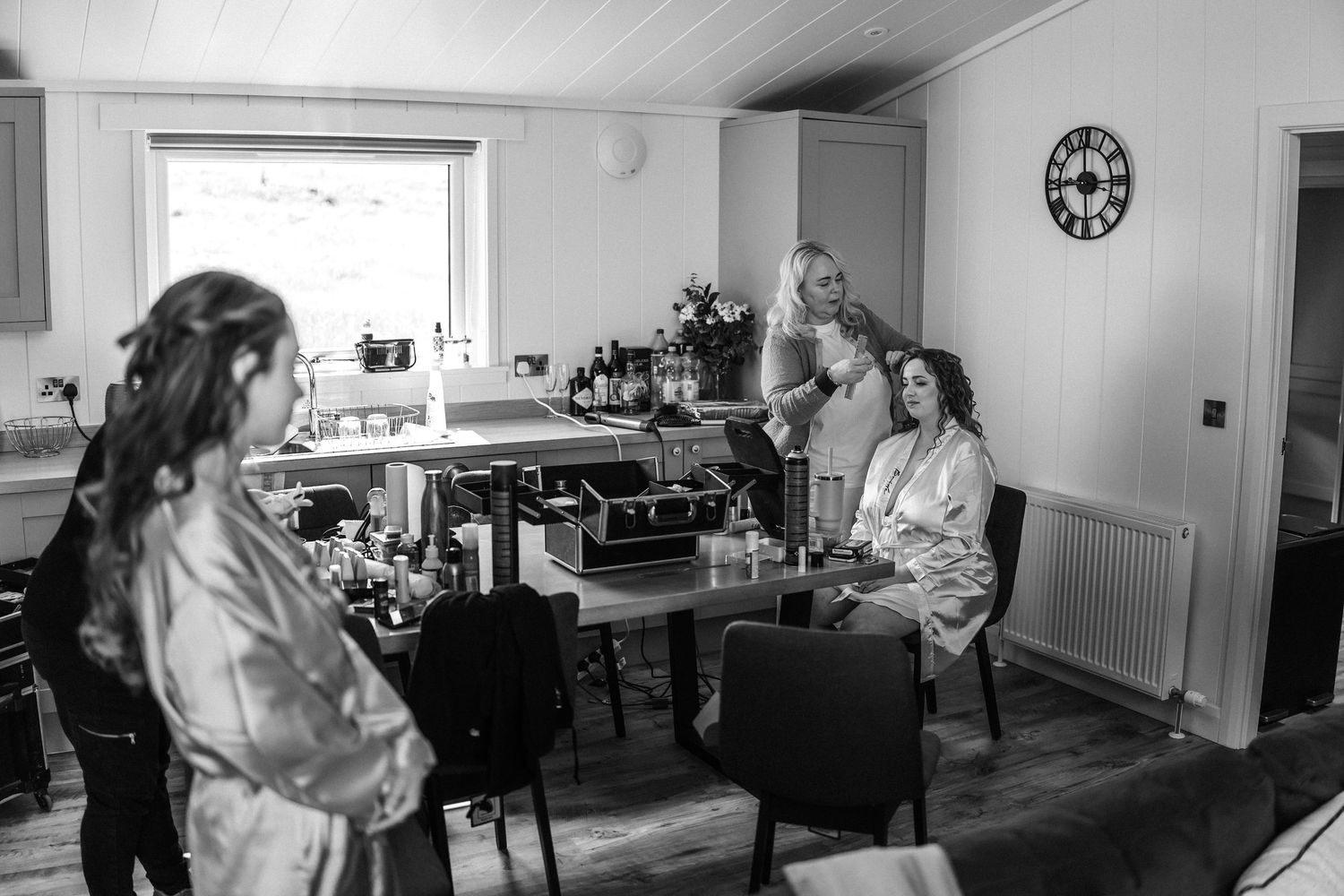 Black and white panoramic view of wedding preparations in a spacious room.