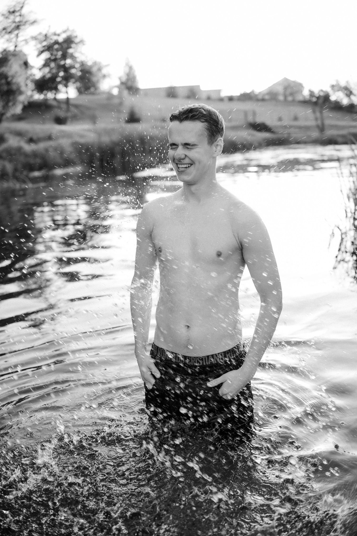 Person splashing in water creates dramatic spray effect in black and white photography.