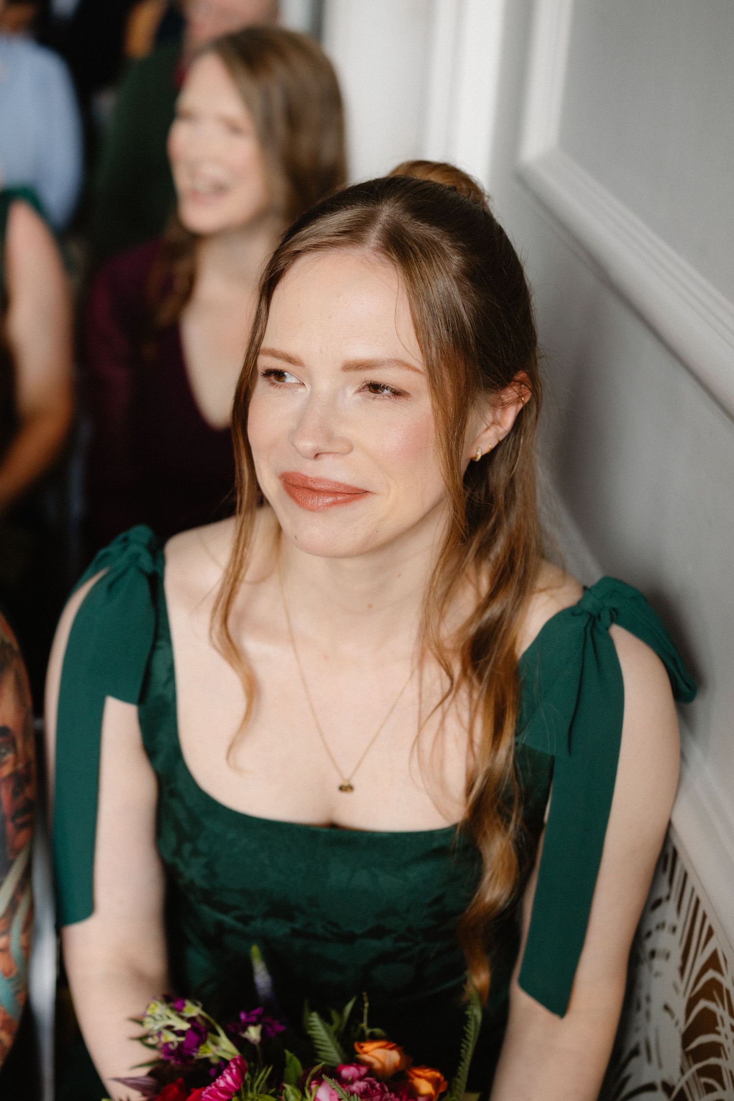 Bridesmaid in an elegant dark green dress holding a colorful bouquet.