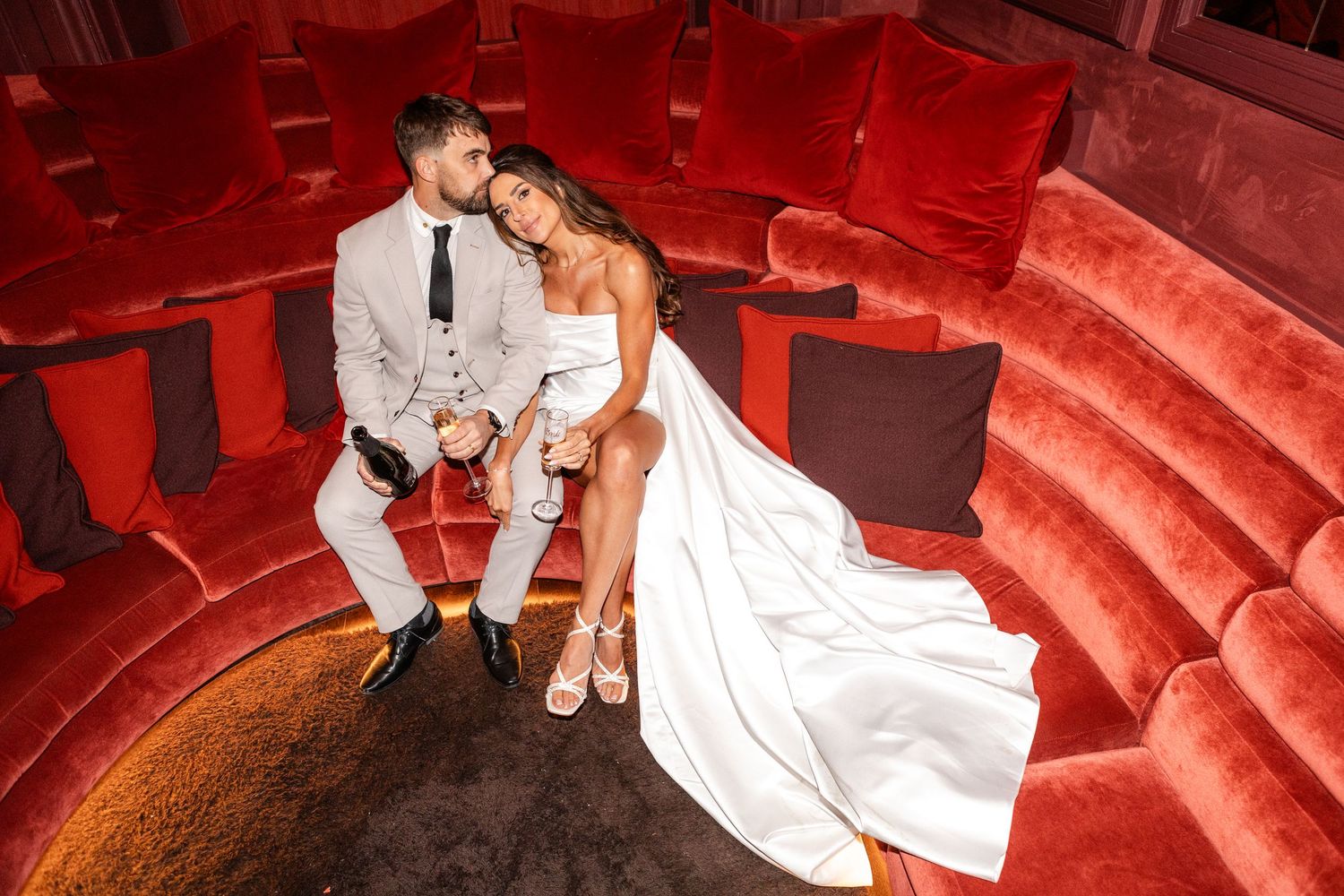 Intimate moments captured on plush red theater seats with dramatic lighting.
