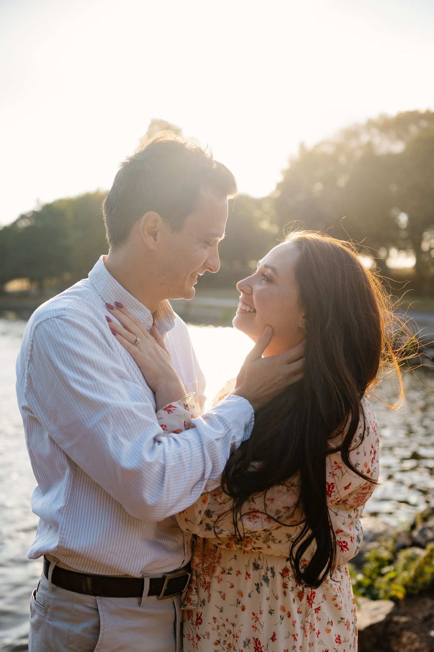 Couple embracing by the water during golden hour sunset.
