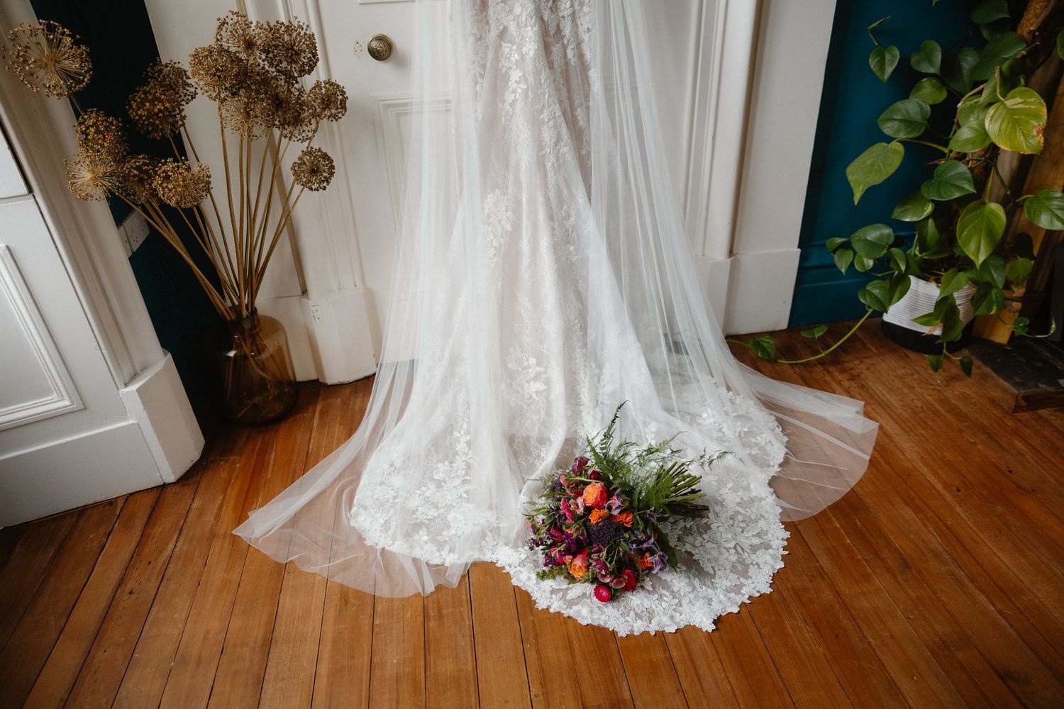 Detail shots of white wedding dress hem against wooden flooring.