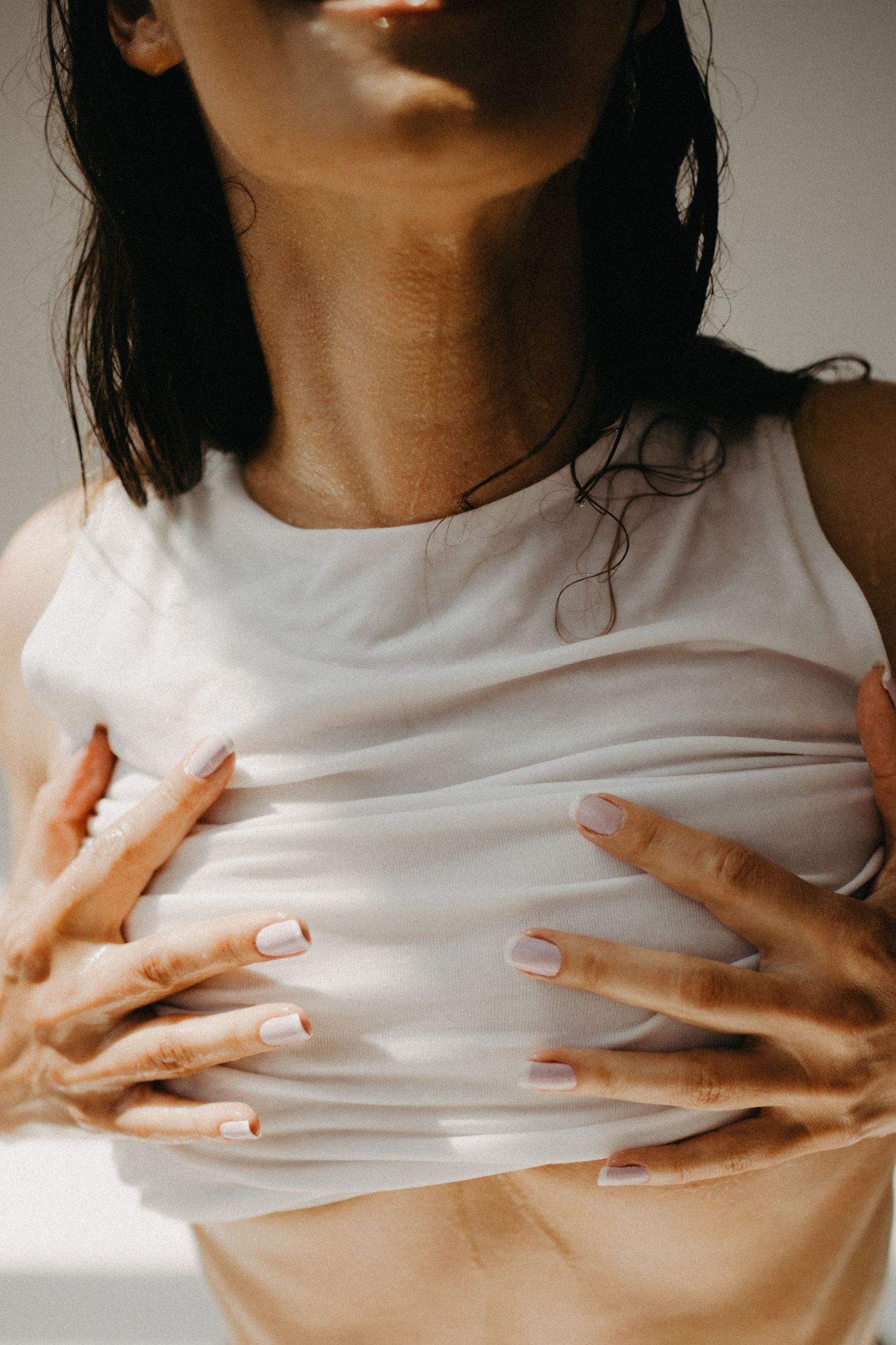 Close-up of hands grasping white fabric in natural light.