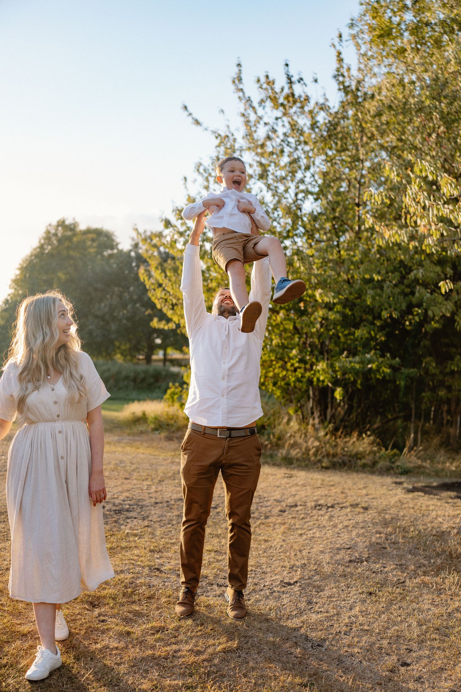 Family walking together in a golden field during sunset wearing coordinated white and brown outfits.