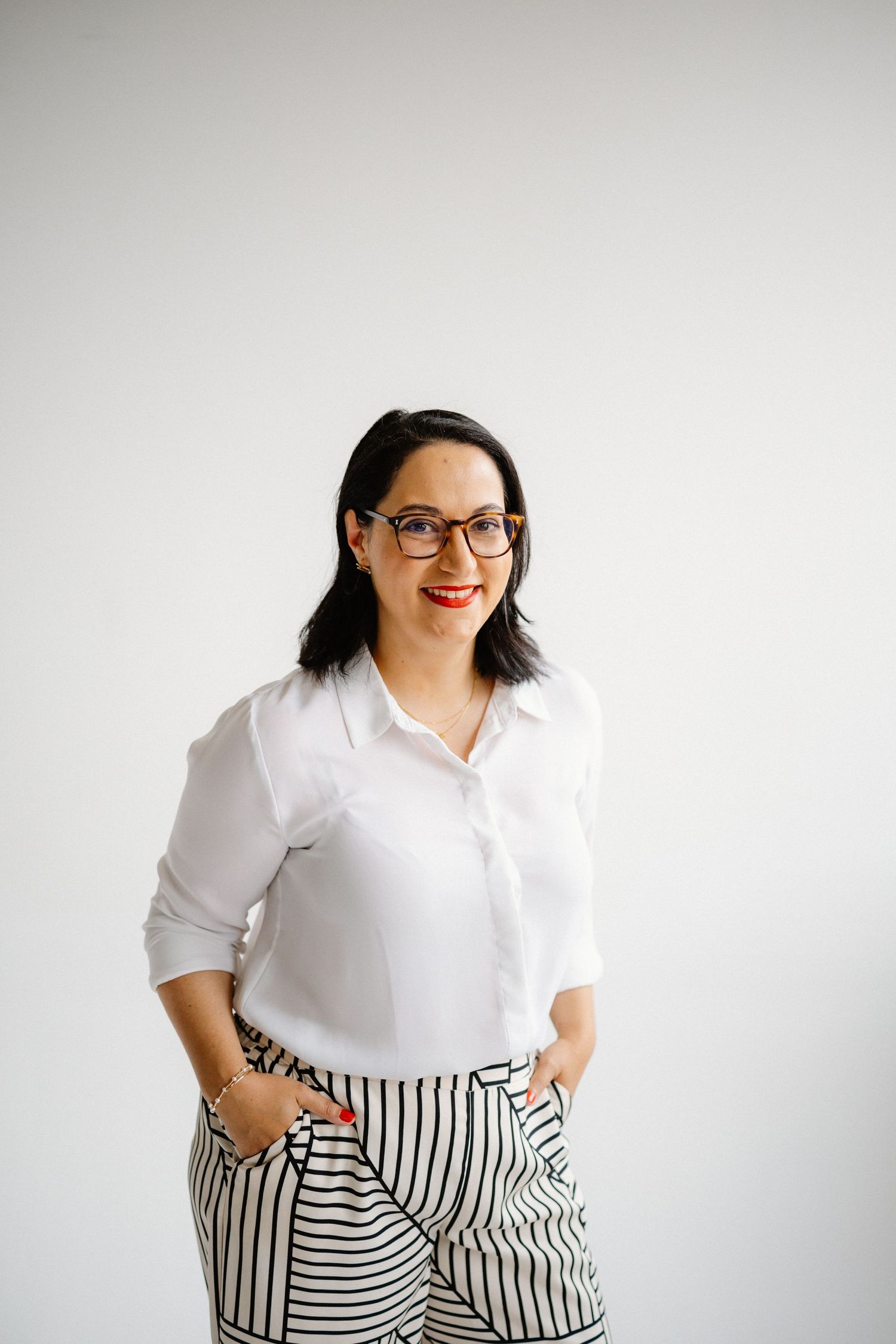 Professional portrait of a person in glasses and white shirt against a light background.