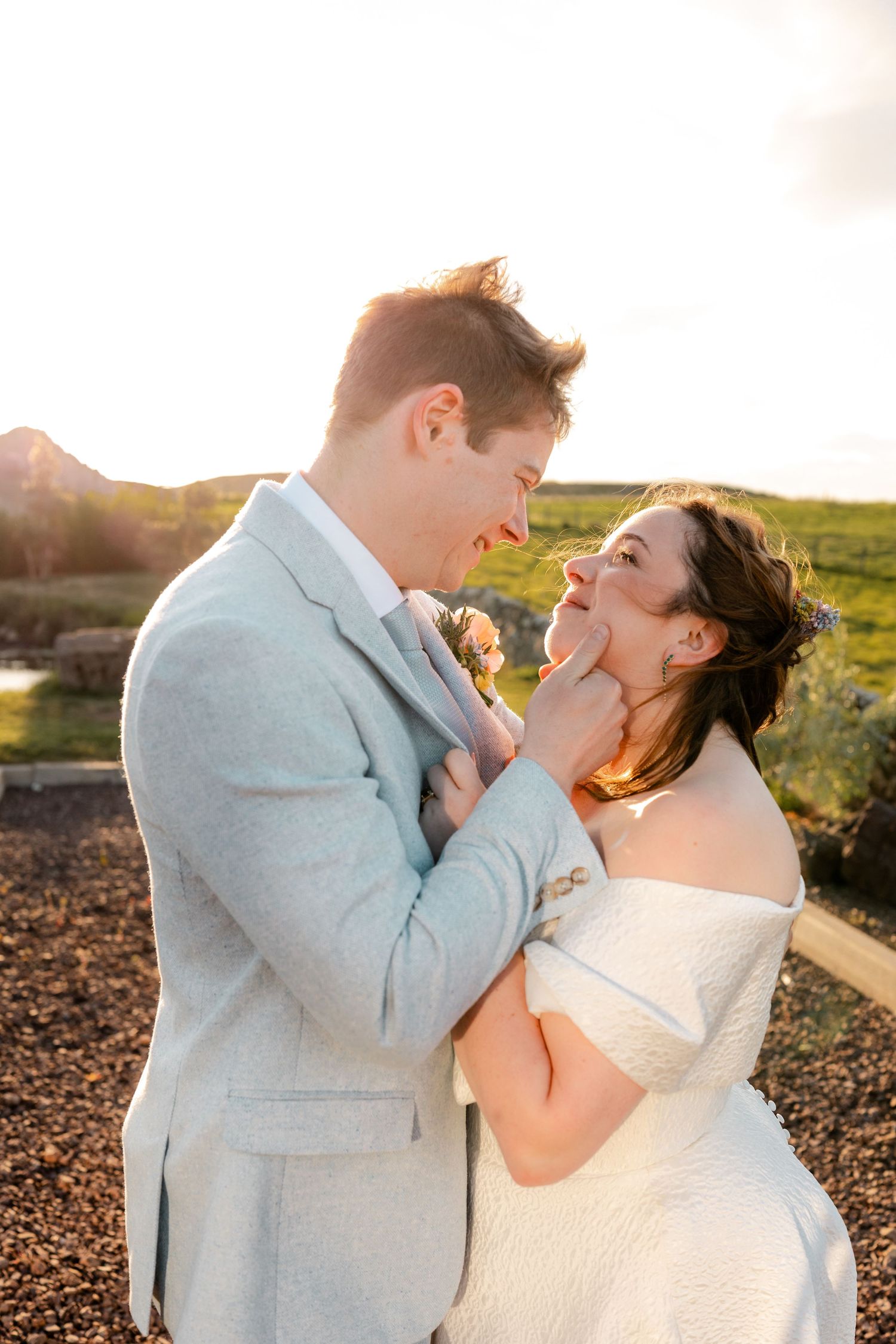 Bride and groom laugh joyfully together in golden sunset light during outdoor wedding portraits.